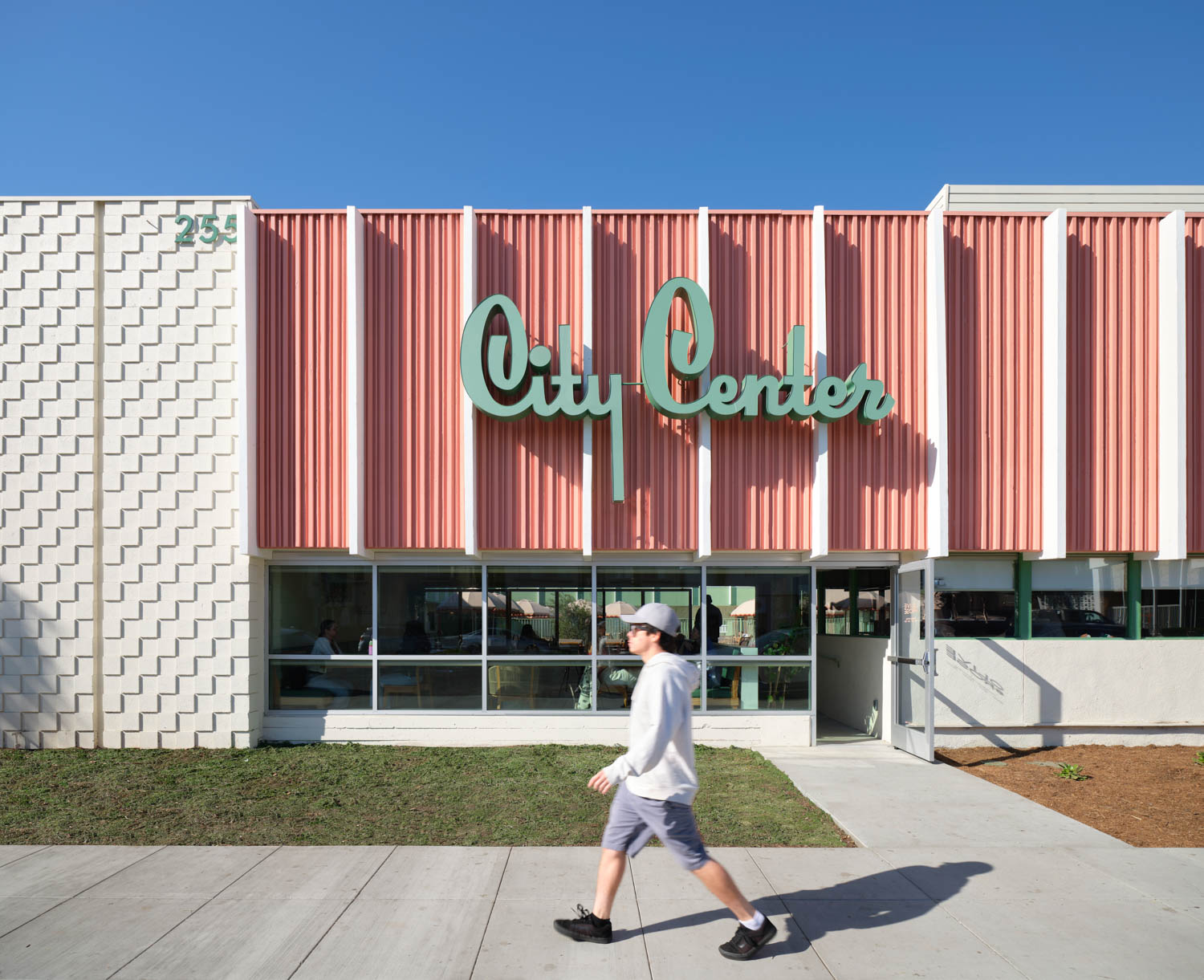 person walking in front of motel with pink and green signage