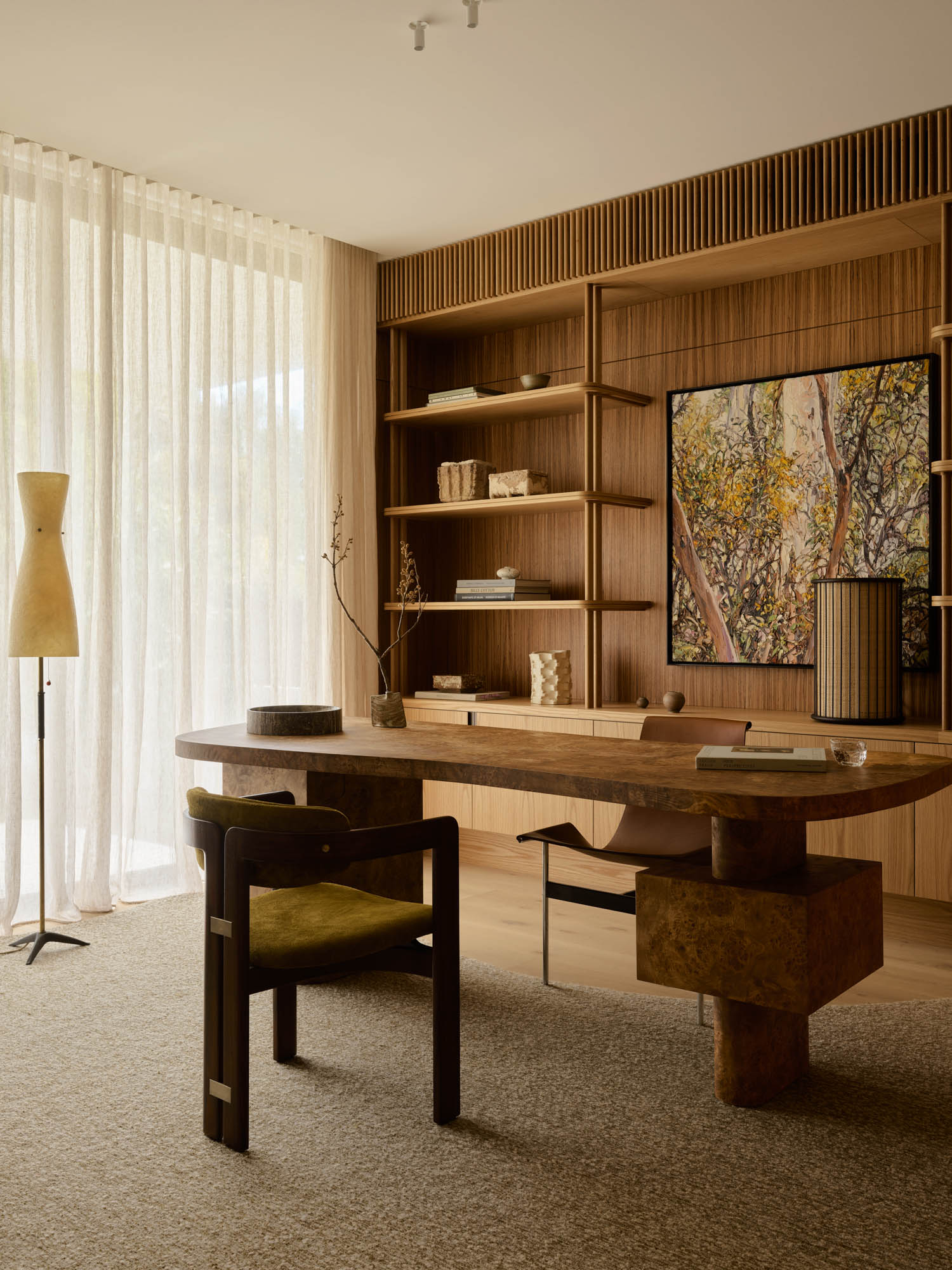 study with dark olive green chair and wooden shelves