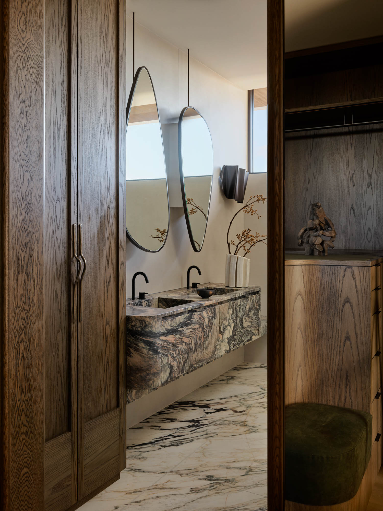 primary suite bathroom with wooden wardrobe and marble sink