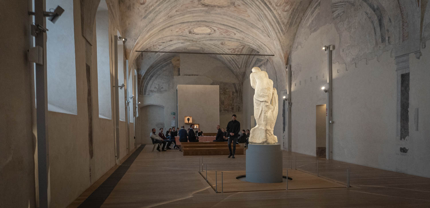 the sculpture from behind in a long hall
