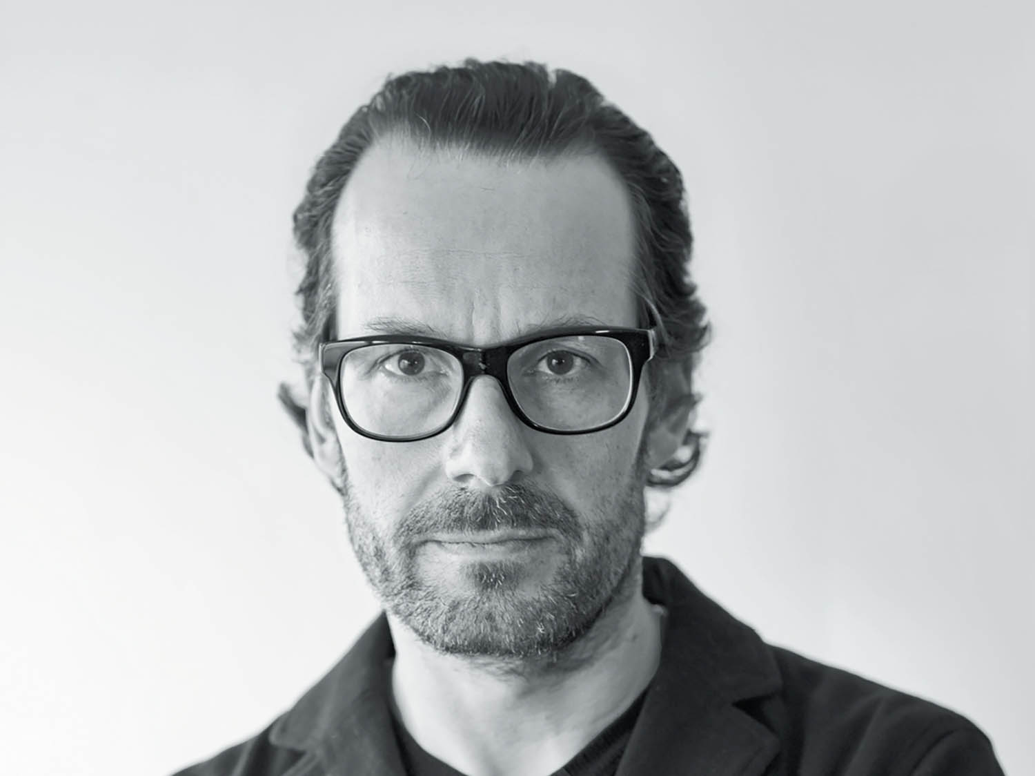 A man with glasses and a black shirt.