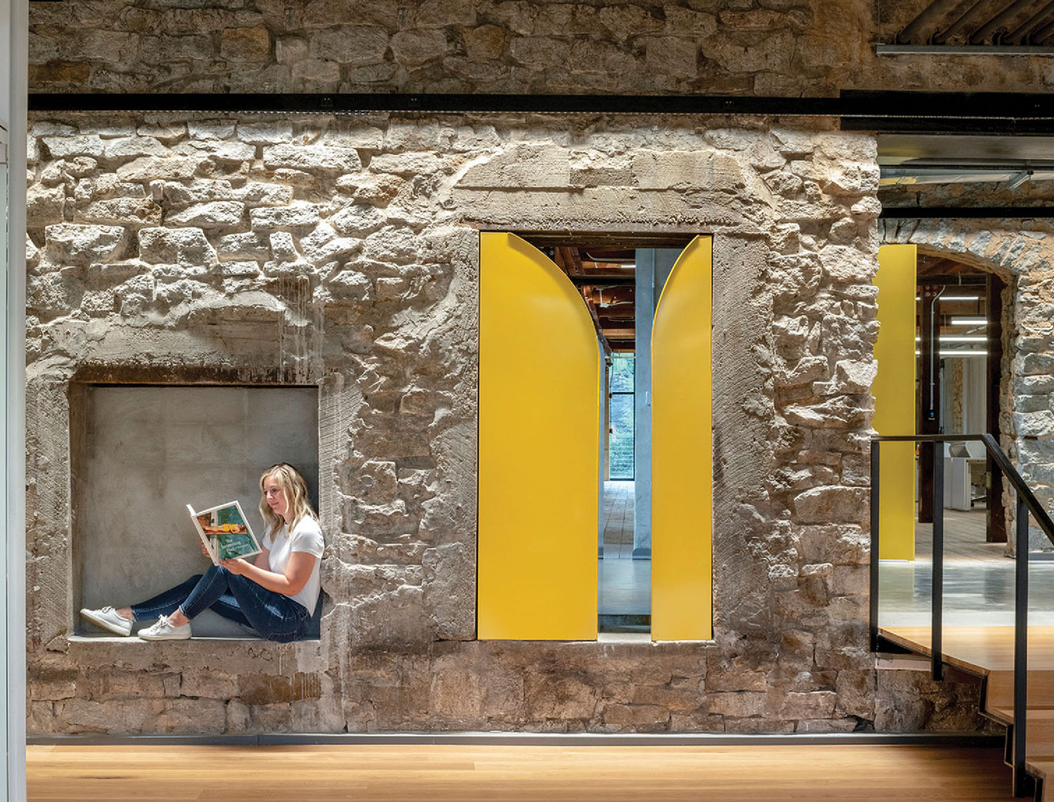 A woman sitting on a ledge reading a book