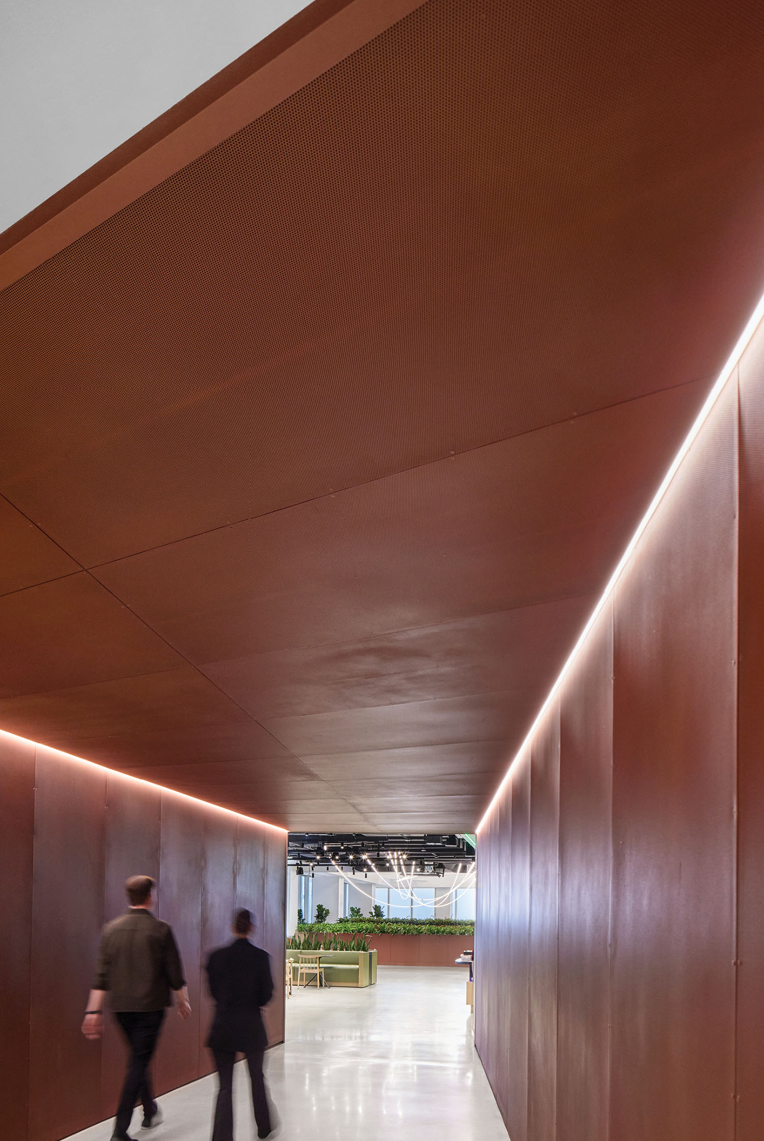 A couple of people walking down a long hallway.