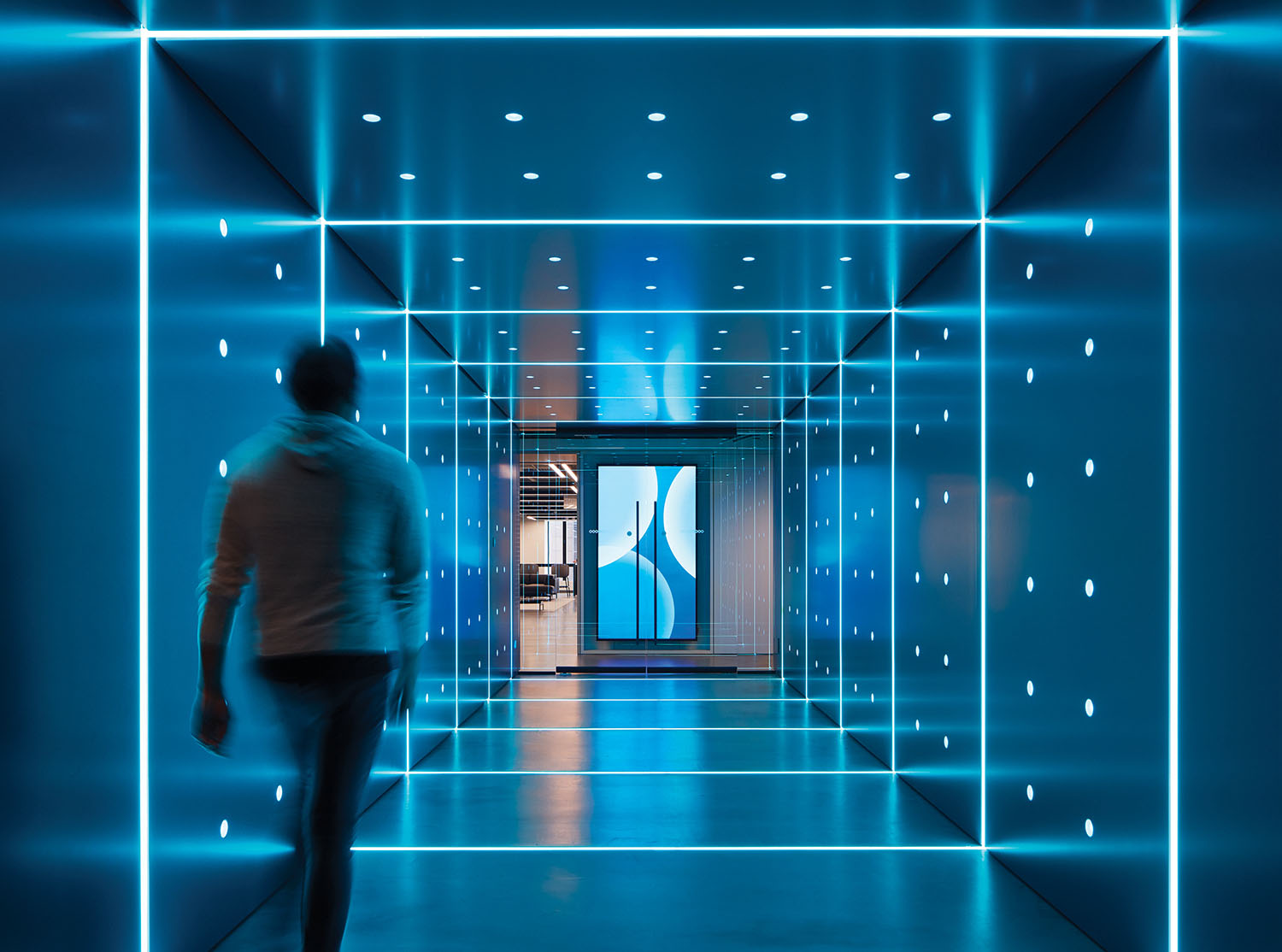 A man walking through a blue tunnel.