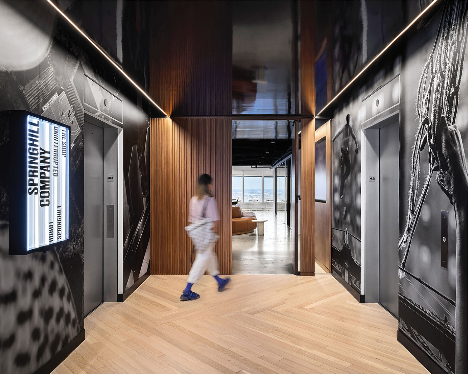 A man walking through a hallway with a large poster on the wall