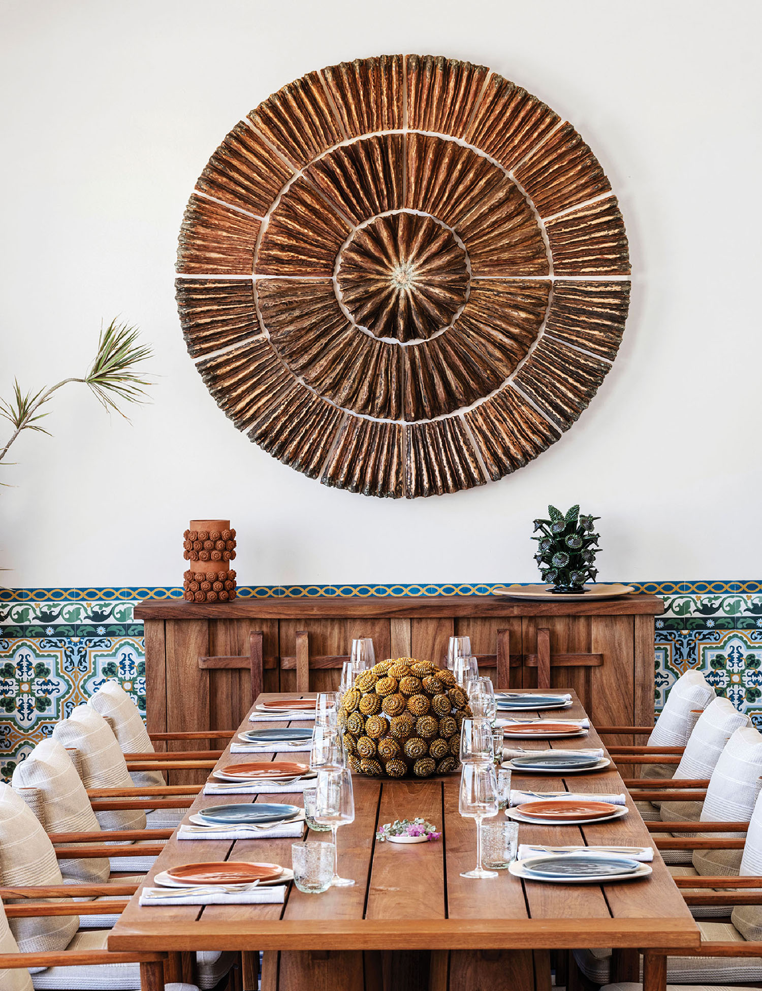 A wooden table with a large sun shaped mirror above it