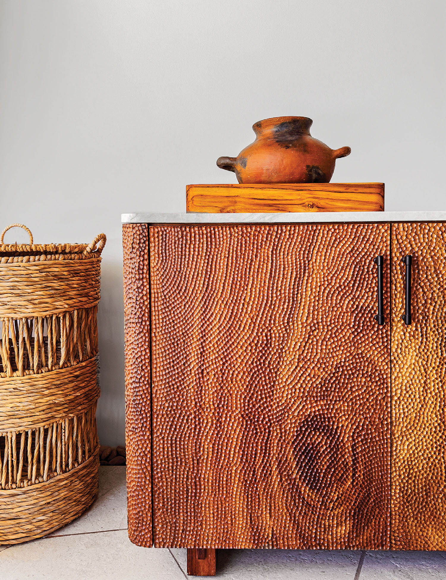 A wooden cabinet with a basket and a vase