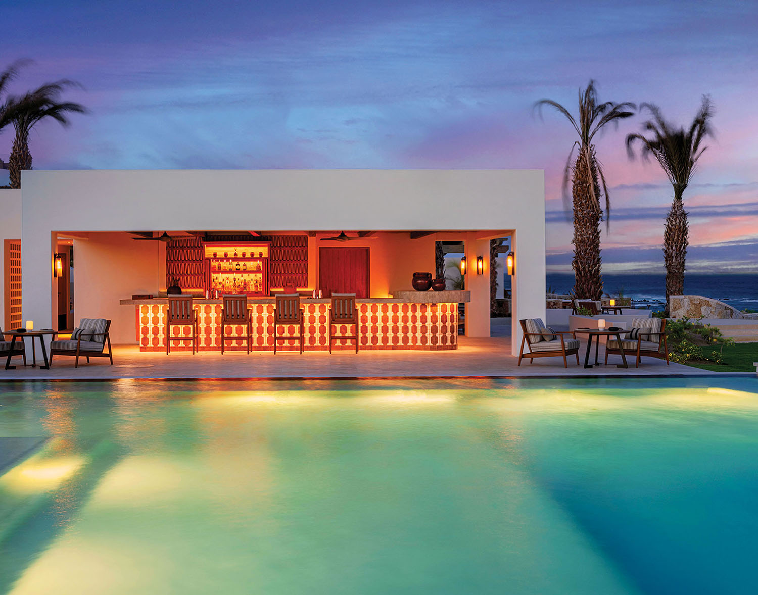 A pool with a bar and chairs next to it