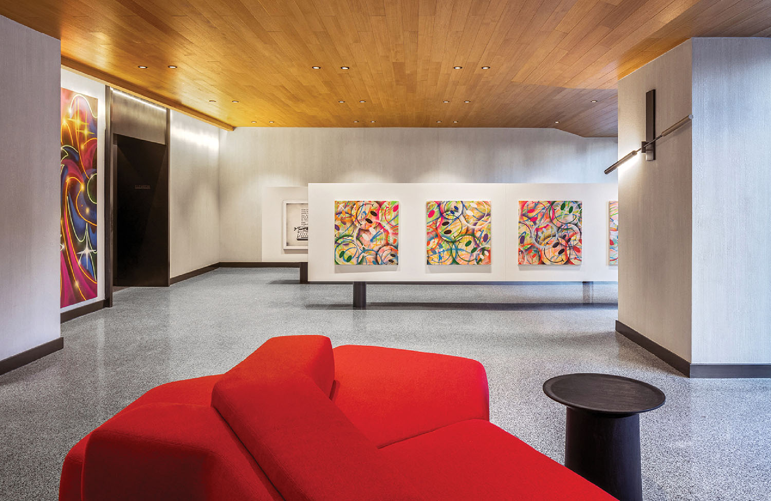A red couch in a room with a painting on the wall