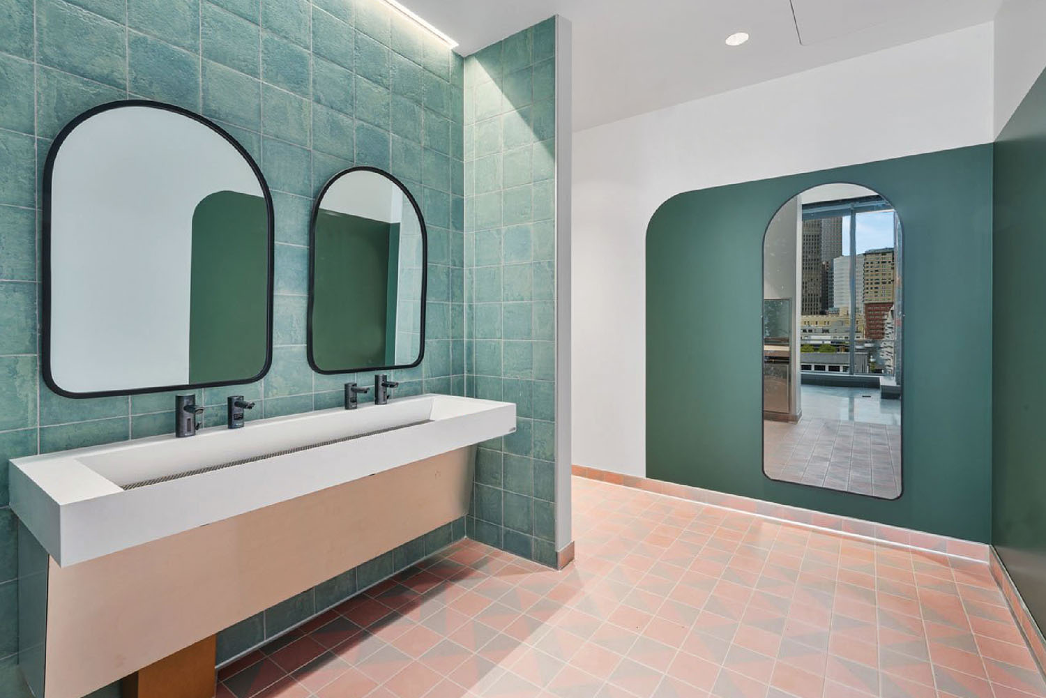 A bathroom with green tiles and a mirror