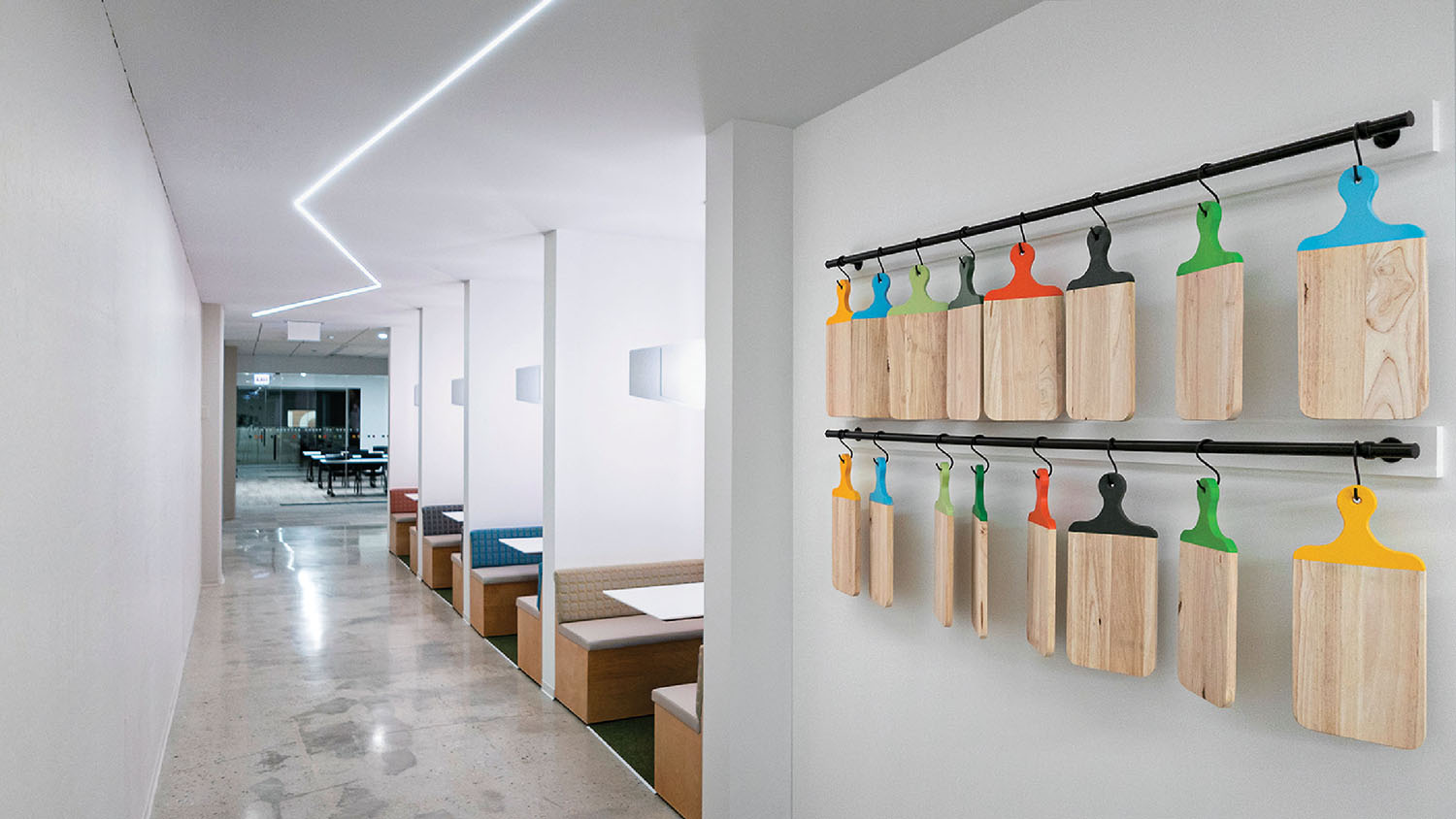 A long hallway with a long wall with wooden hangers