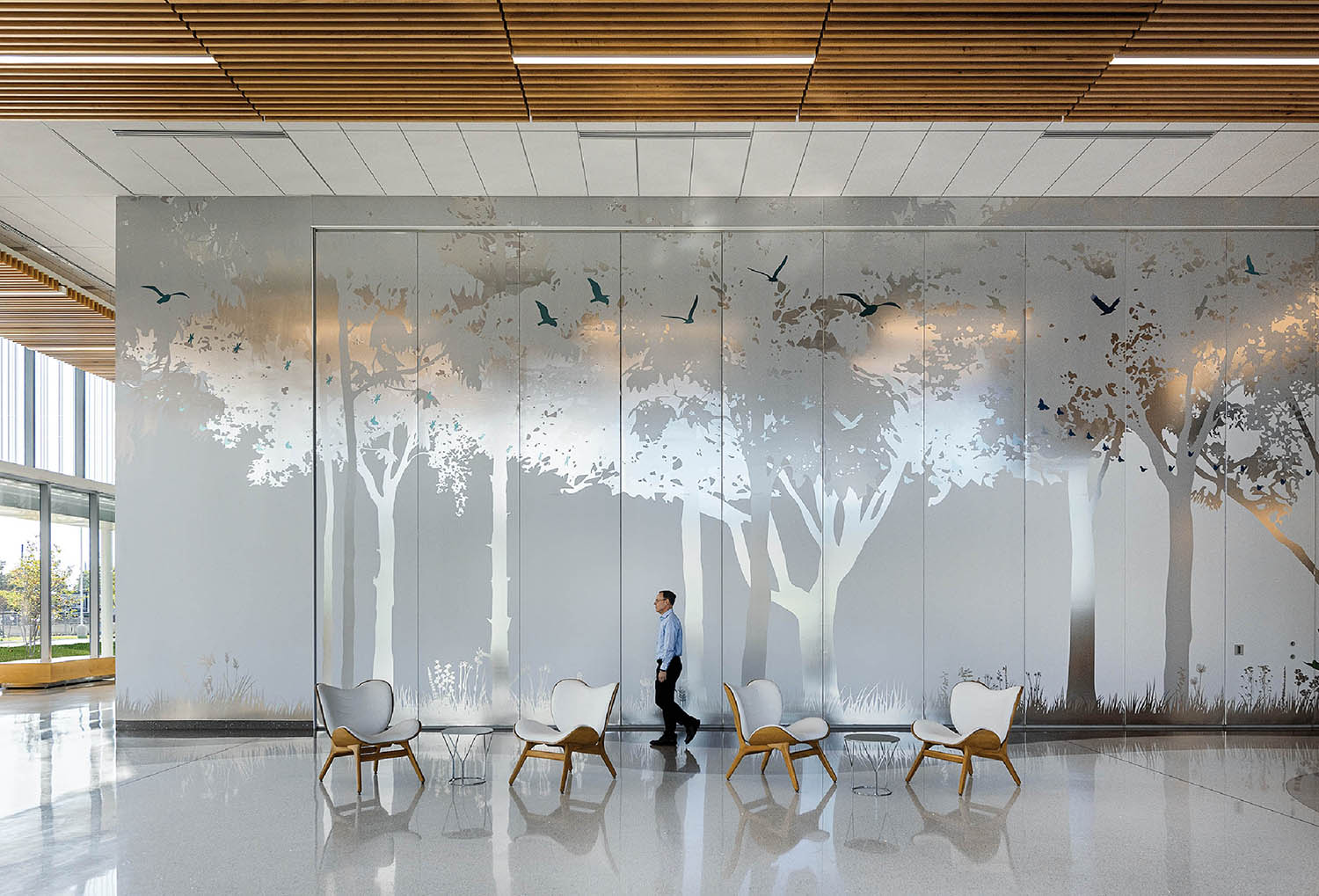 A man walking through a lobby with a mural on the wall