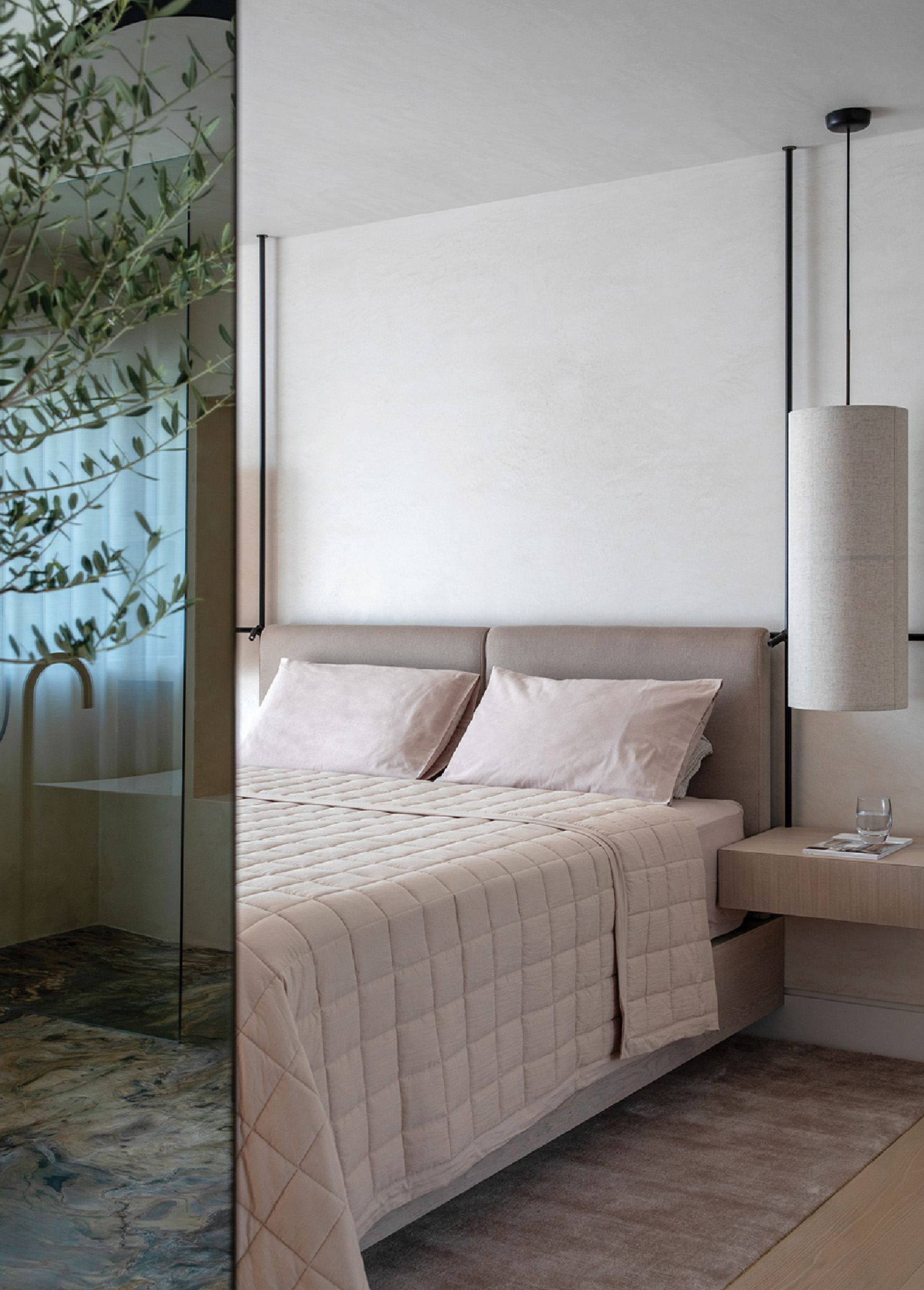 A bedroom with a bed and a plant in the corner.