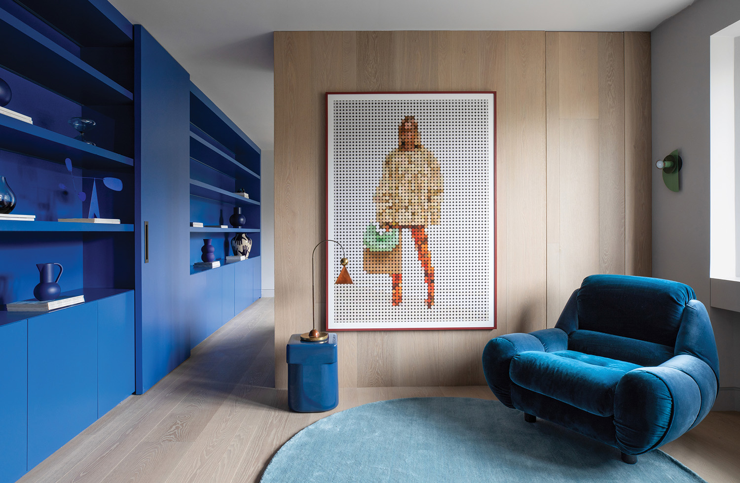 A blue chair in a room with a picture on the wall.