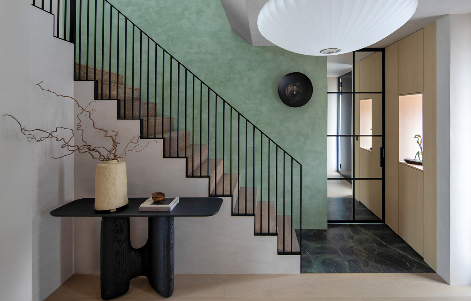 A staircase with a table and a vase.