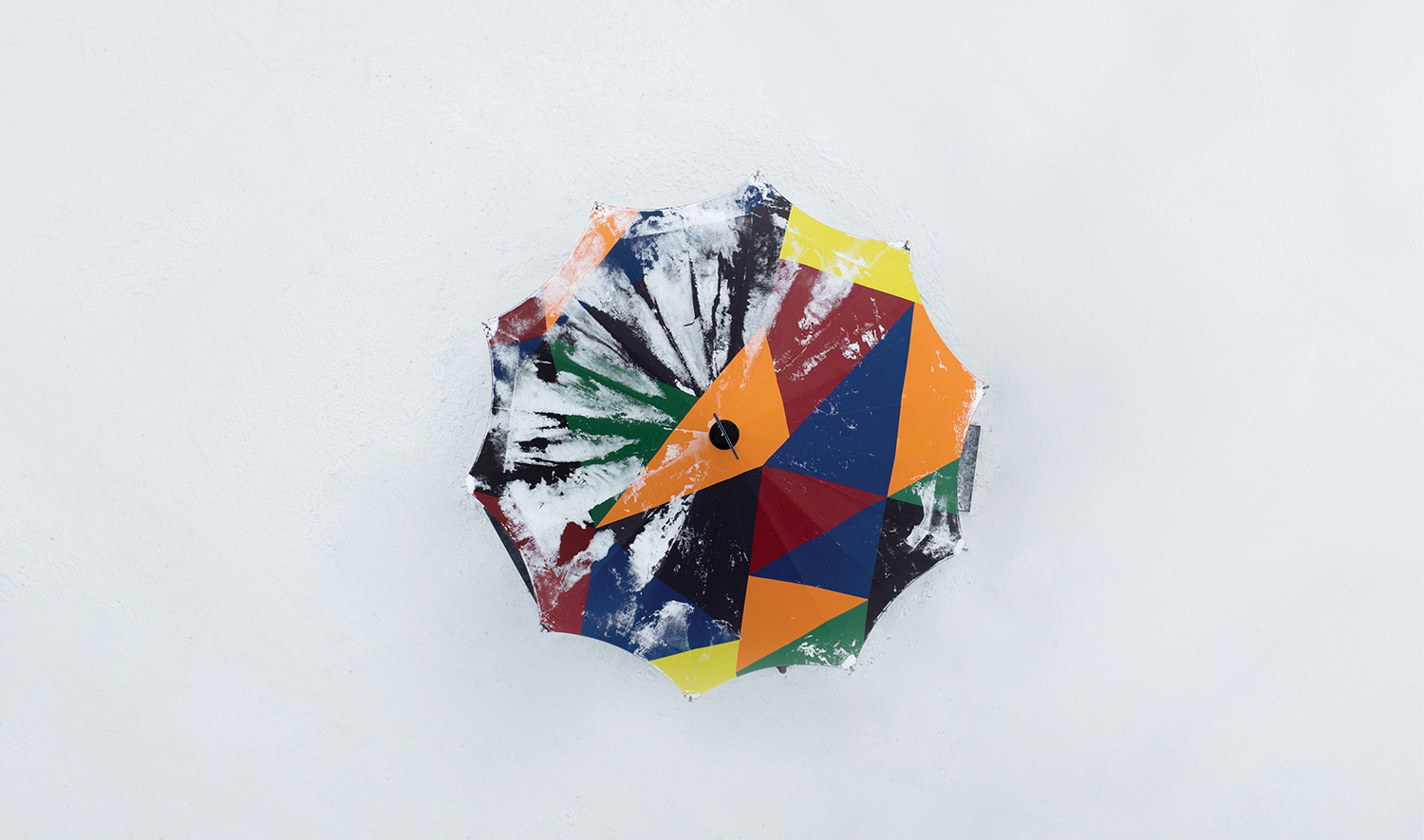 A colorful umbrella is stuck to the wall.