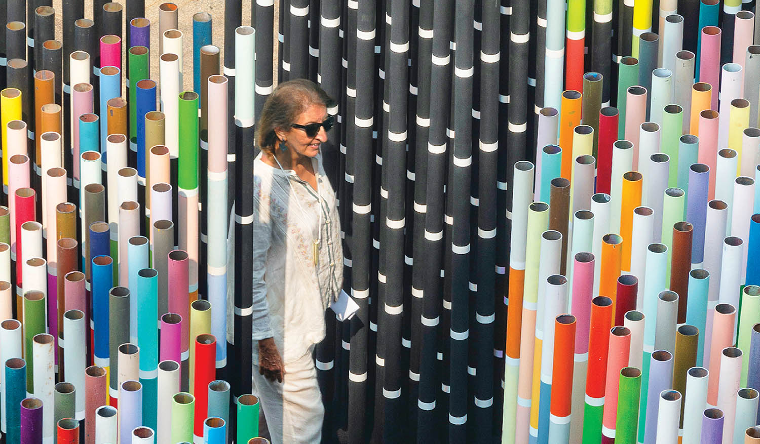 A woman standing in front of a wall of colorful paper.