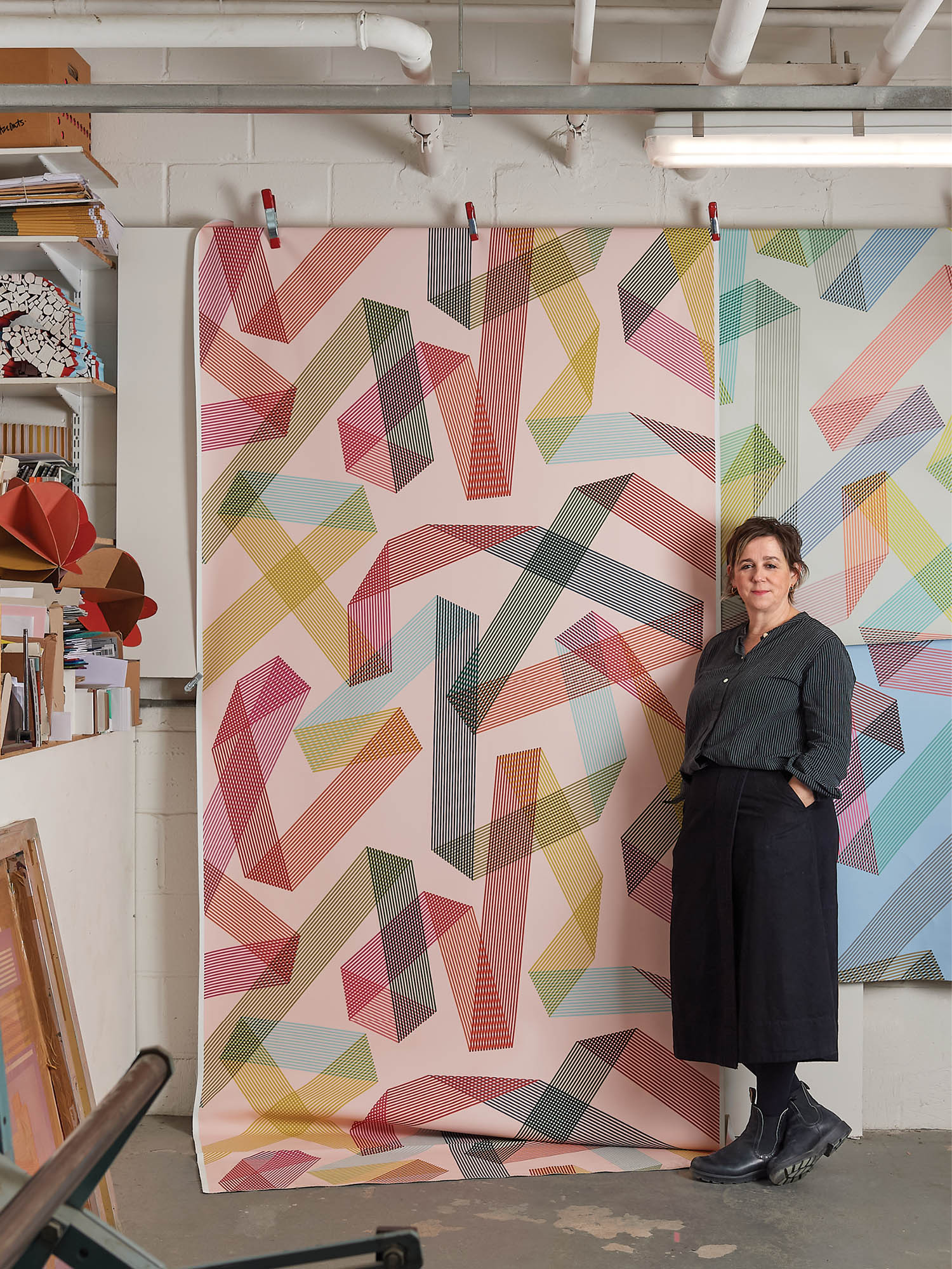 A woman standing next to a large wall mural.