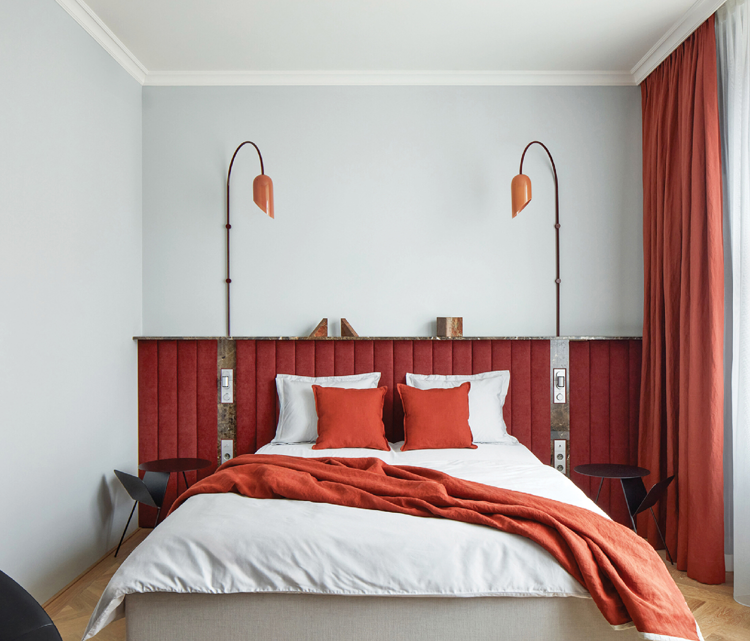 A bed with a red blanket and pillows.