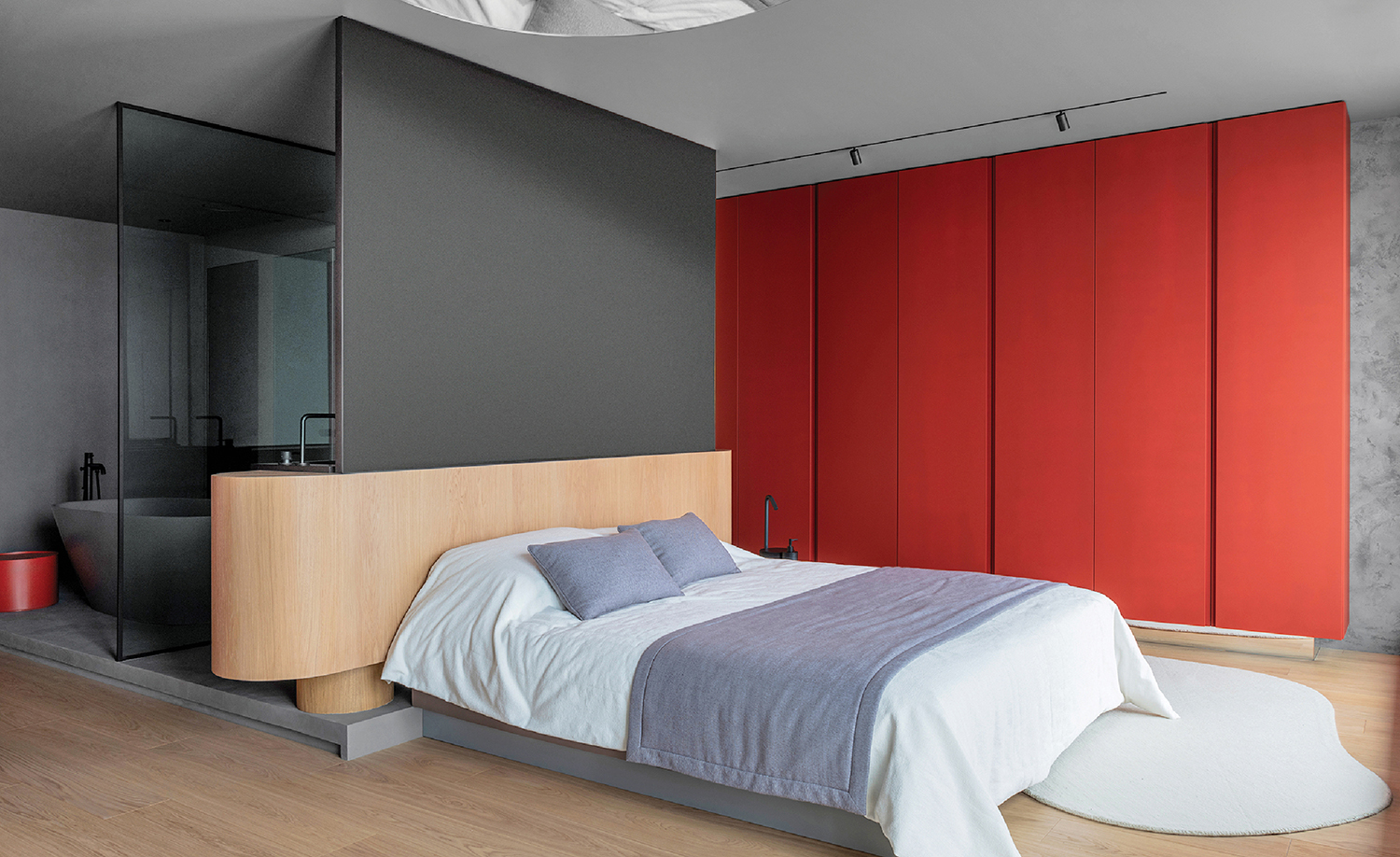 A bedroom with a bed and a red wall.