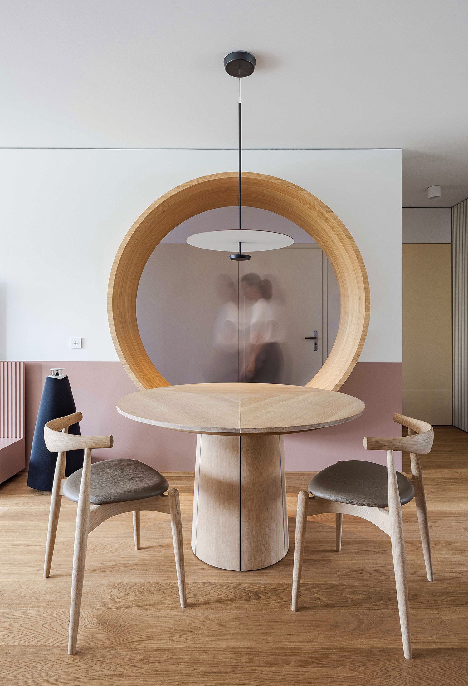 A wooden table with two chairs and a round mirror.