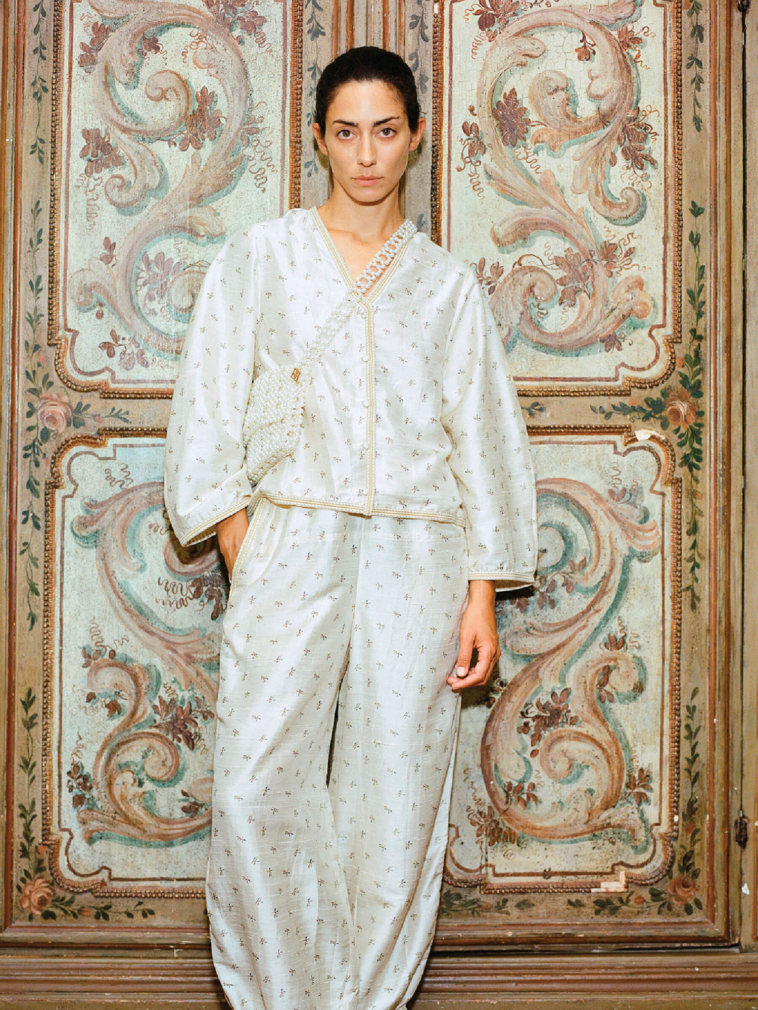 A woman in a white robe standing in front of a wall.