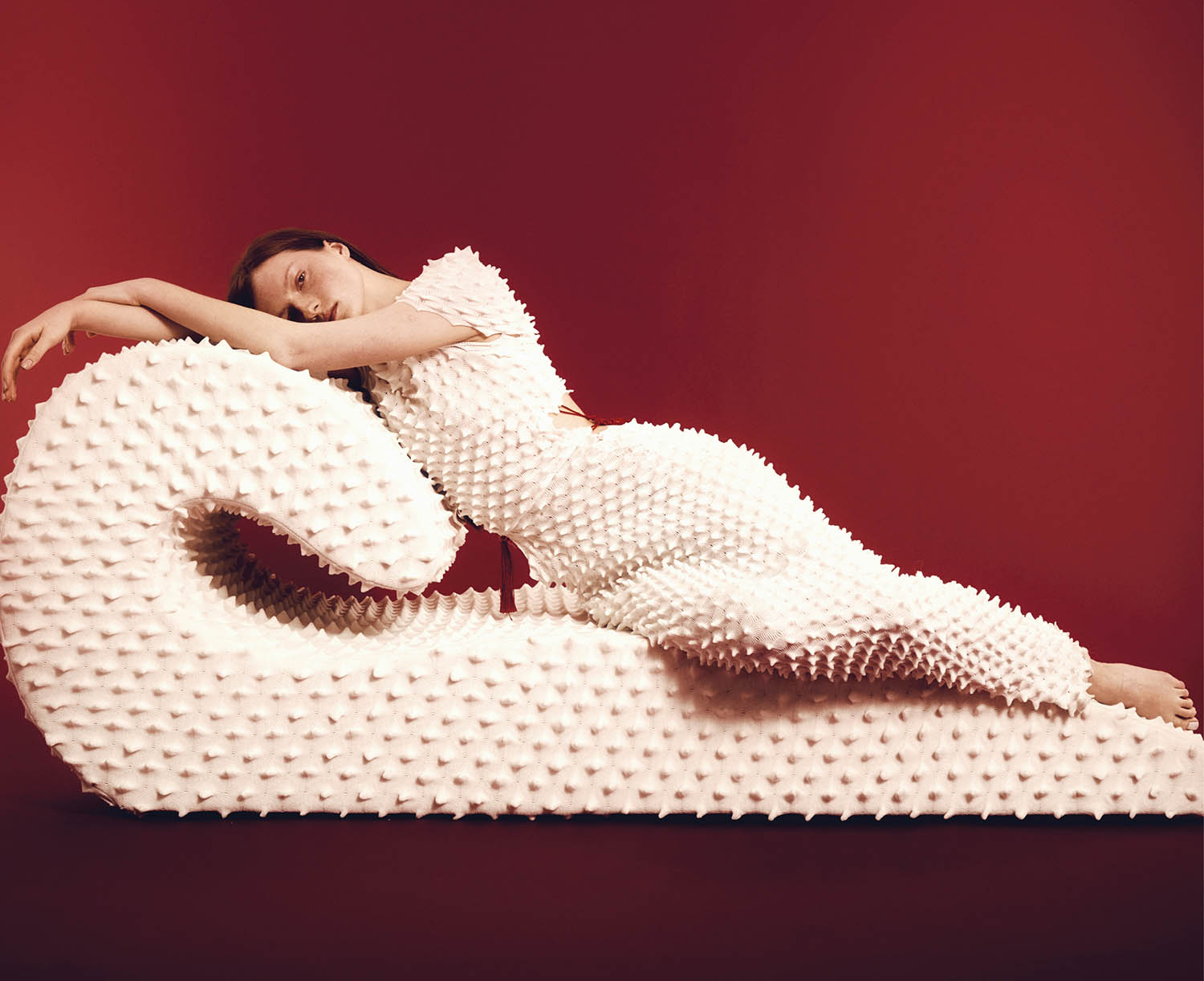 A woman laying on top of a giant white object.