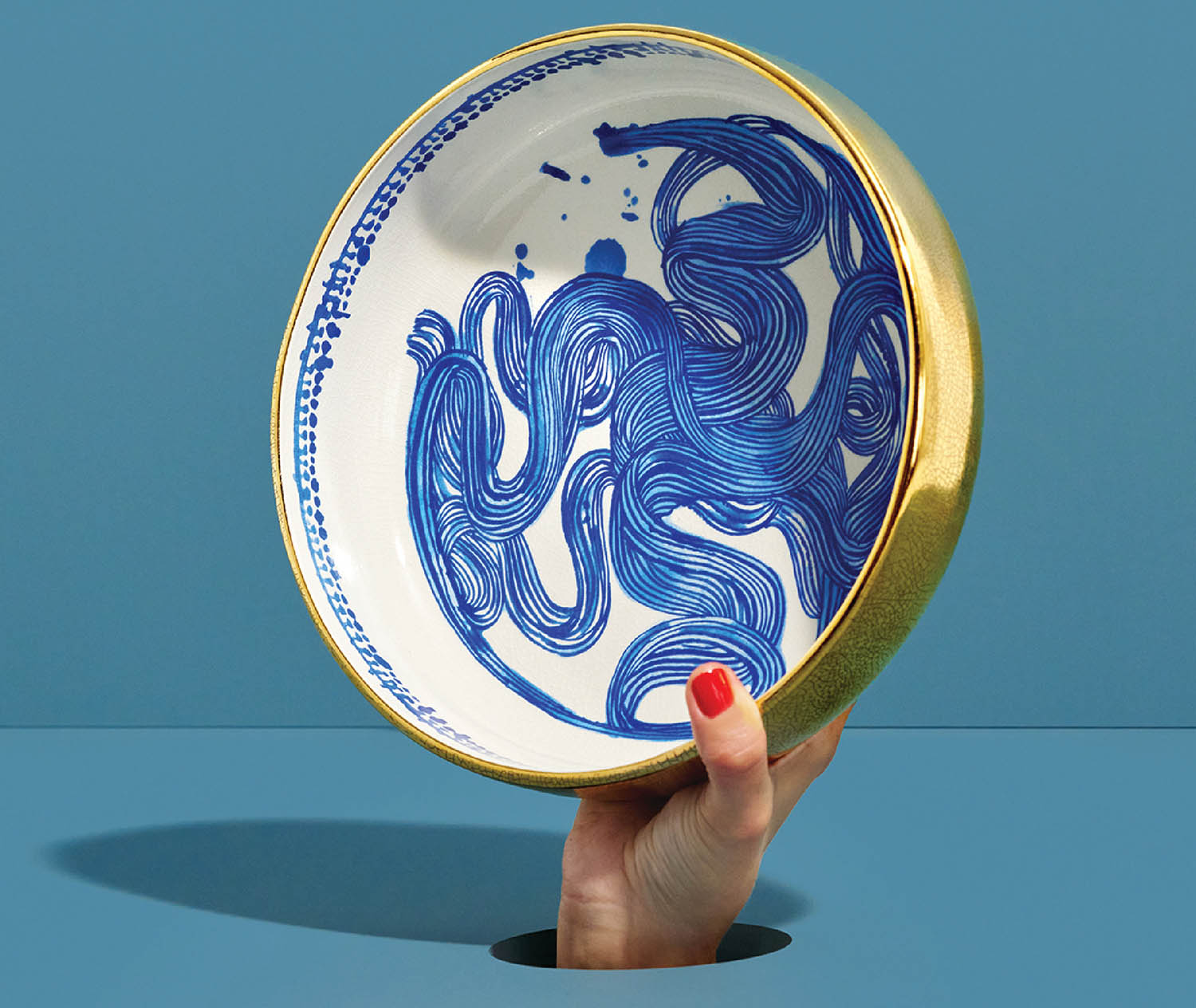A hand holding a blue and white plate.