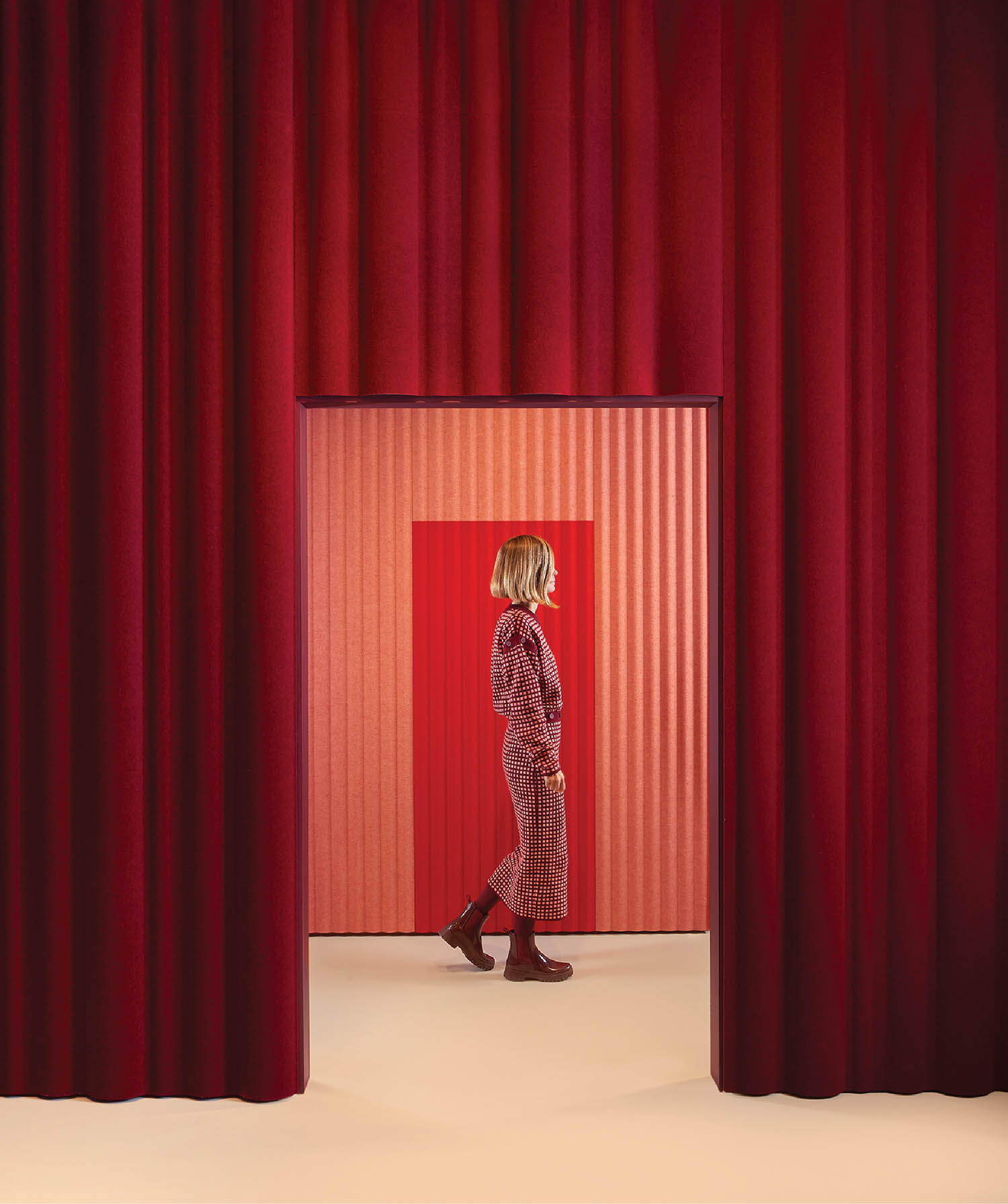 A woman walking through a red curtain.