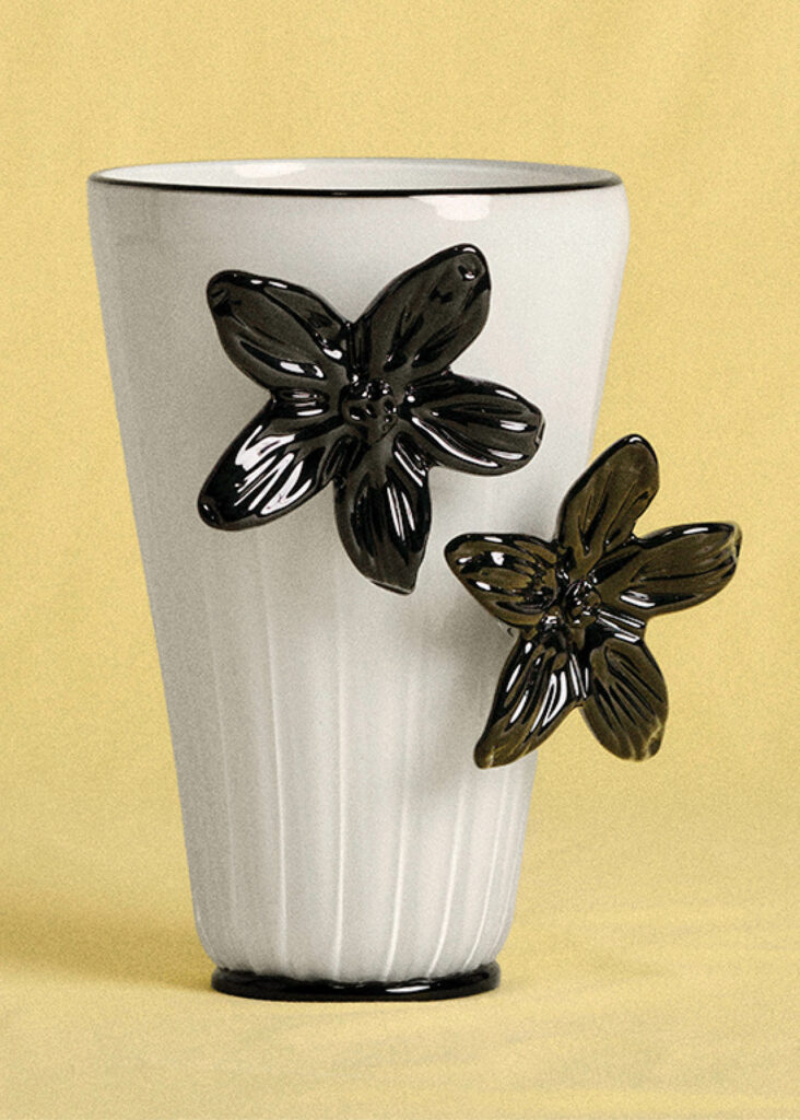 A white vase with black flowers.