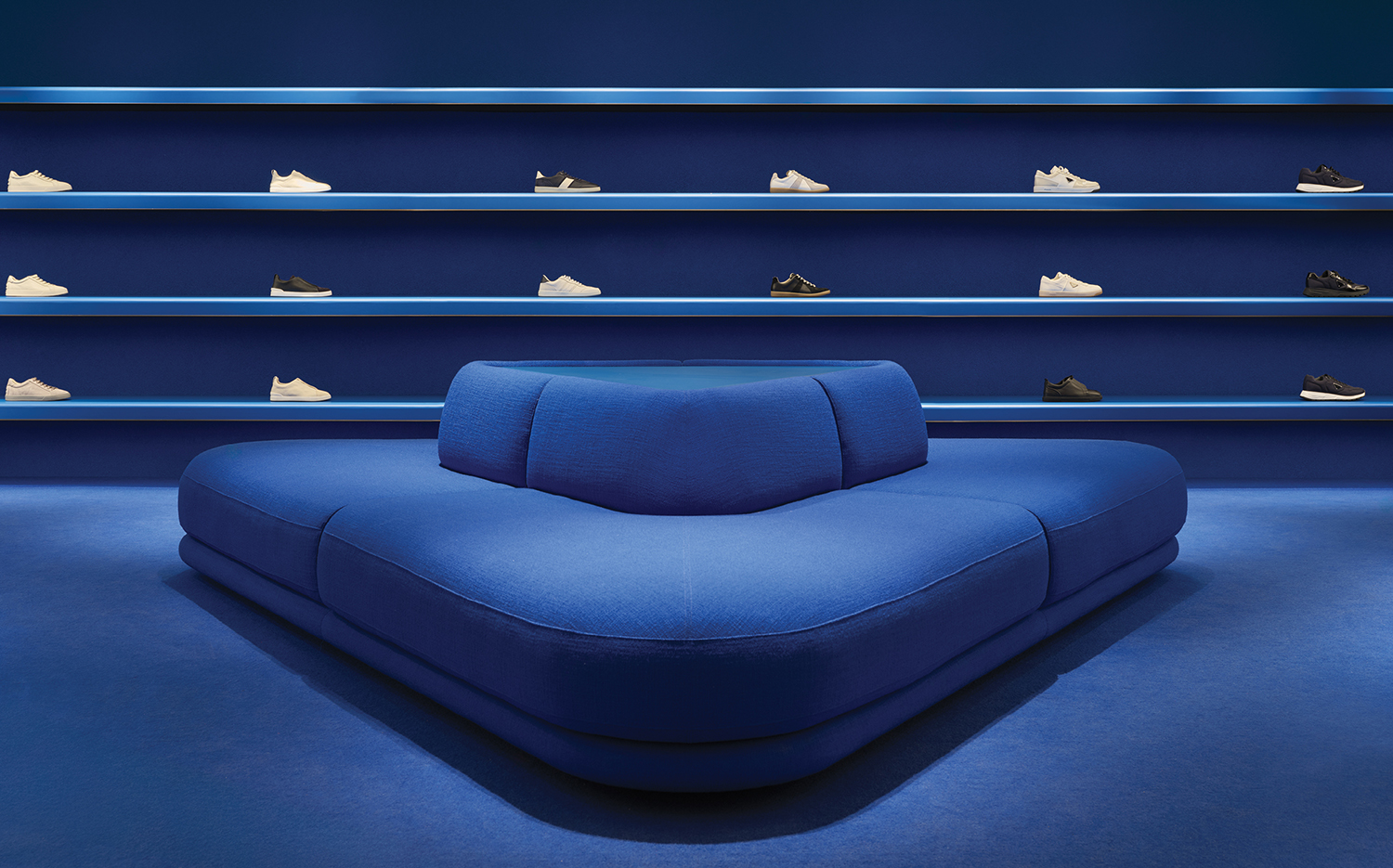 A blue couch with a blue cushion and a blue shelf.