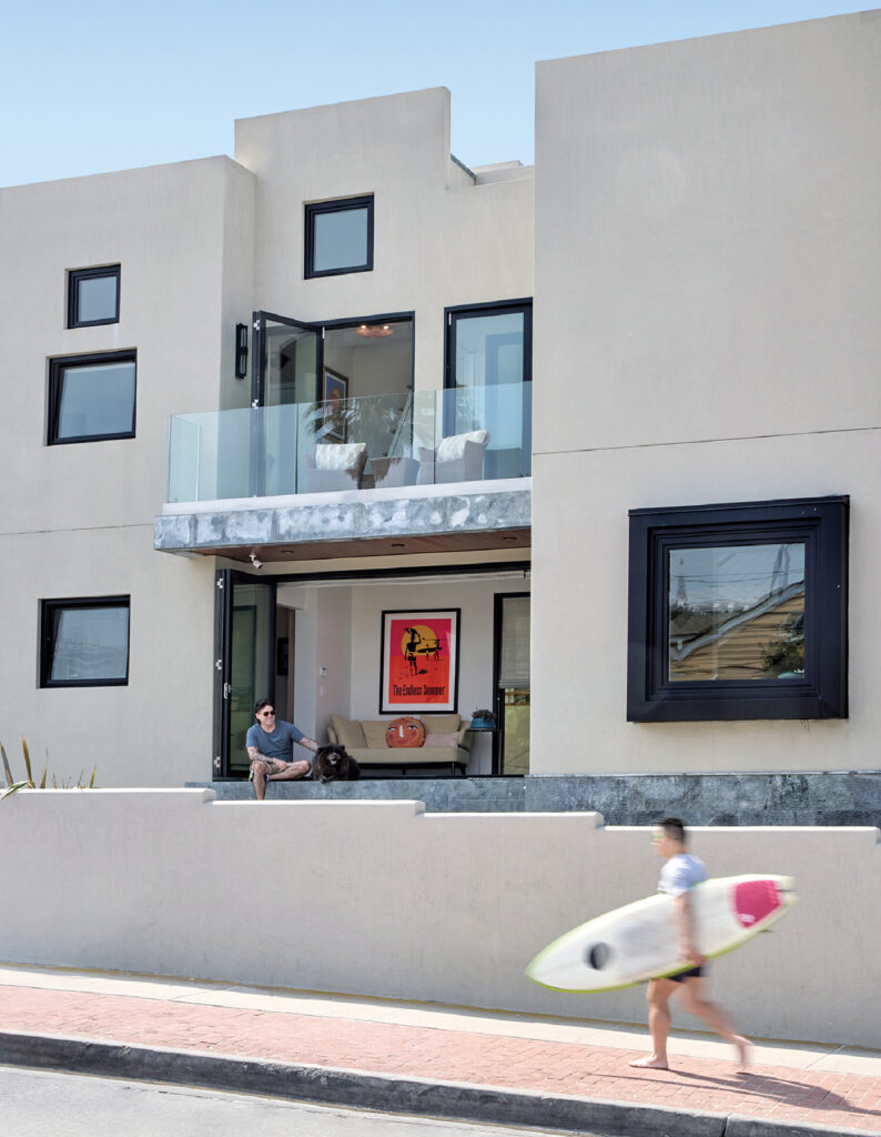 A man walking down a sidewalk carrying a surfboard.