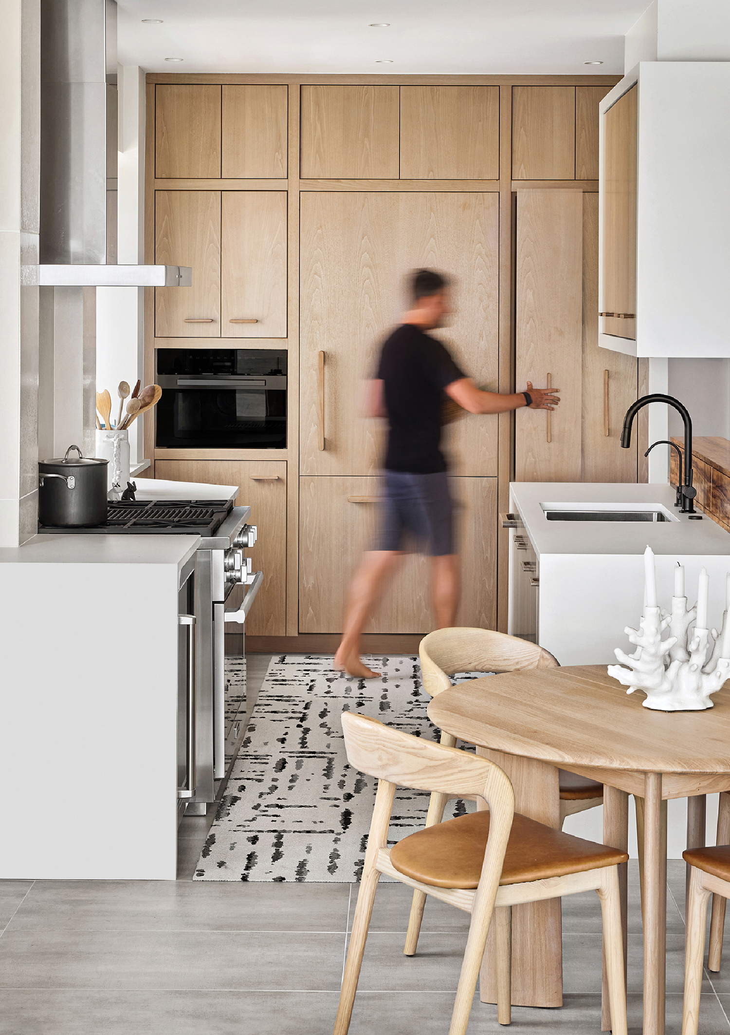 A woman is running in a kitchen with a table.