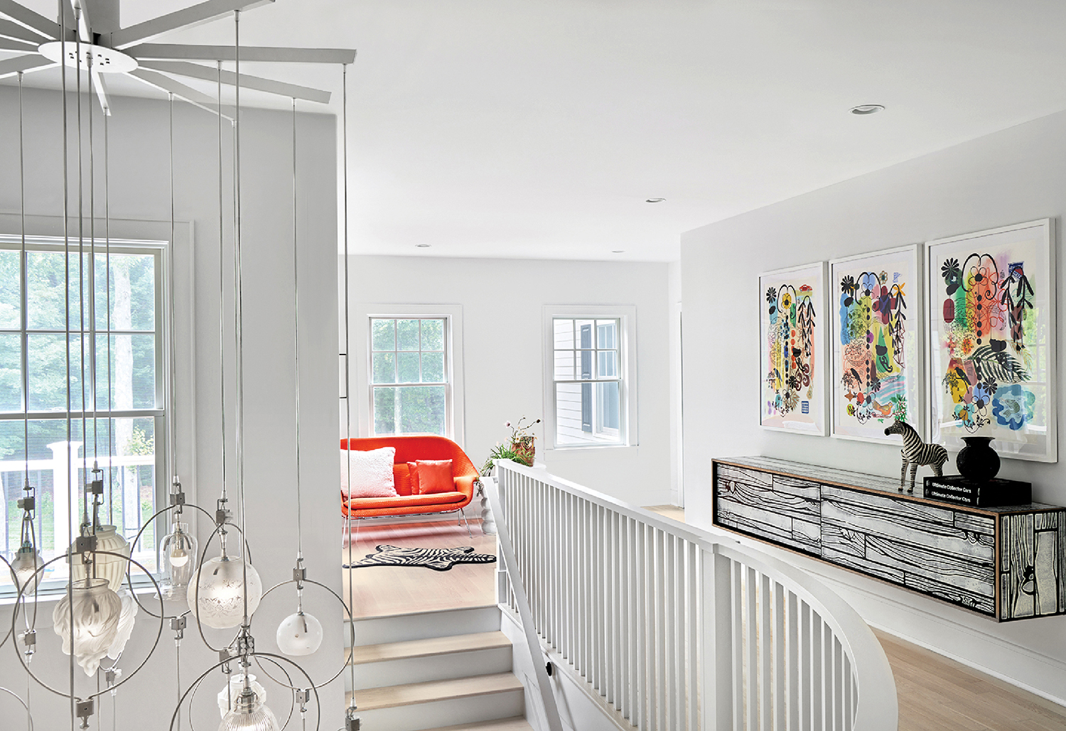 A white staircase with a red chair and a white ceiling fan.