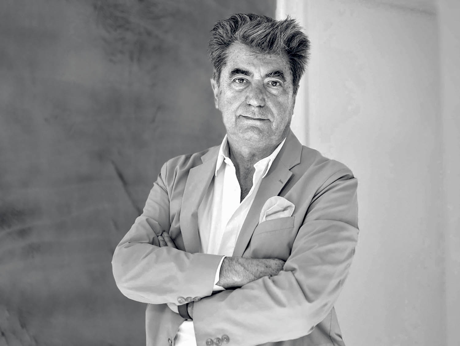 A man in a suit and tie standing with his arms crossed.