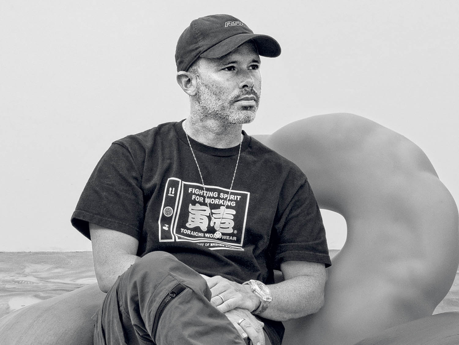 A man sitting on a bed with a hat on.