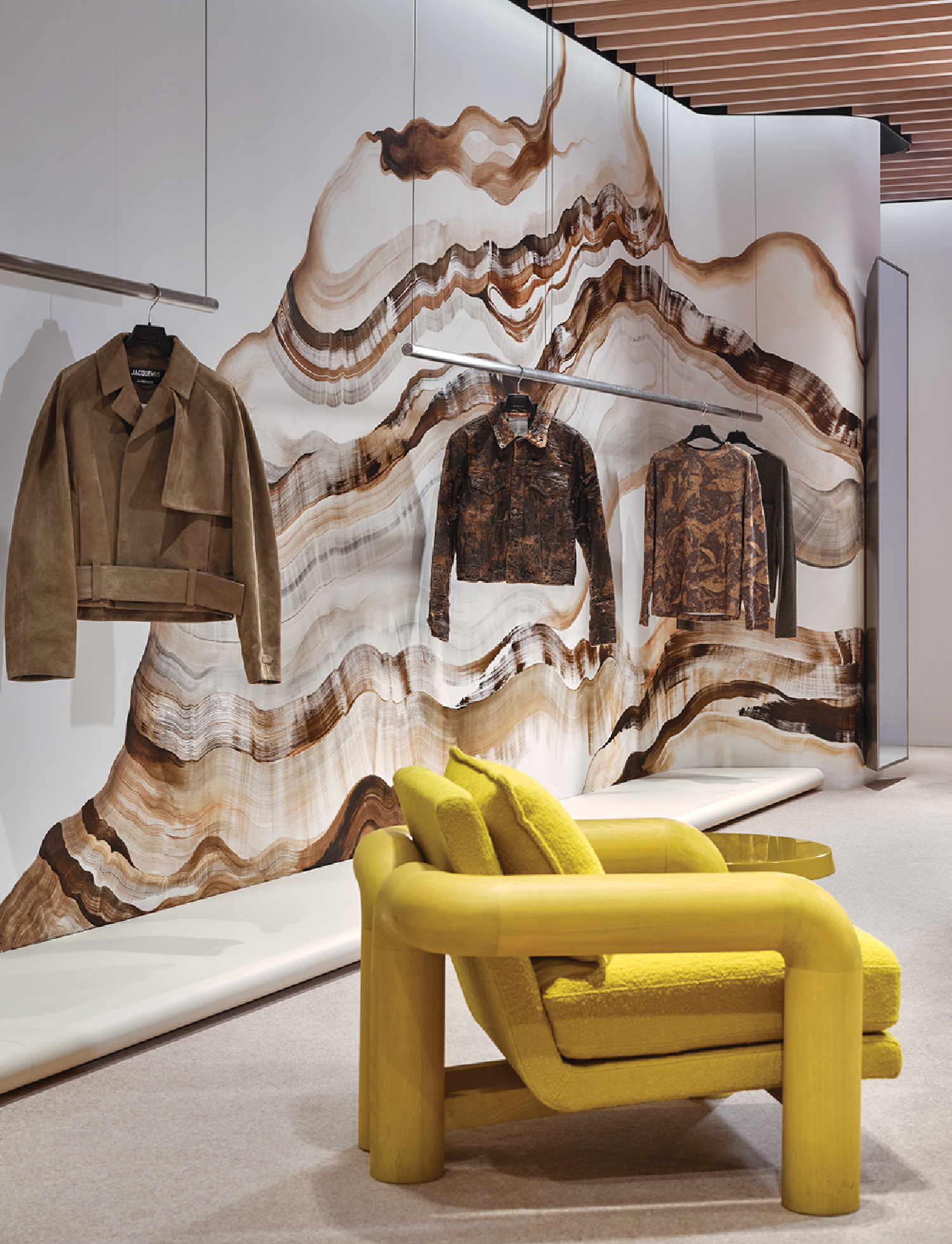 A yellow chair in front of a wall with a painting.