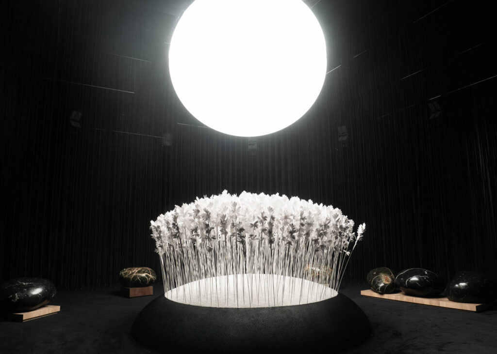 multiple paper flowers under a bright white light with rocks all around