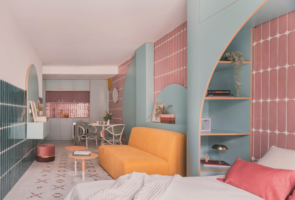colorful kitchen and living room area with light blue walls, pink tiles and orange couch