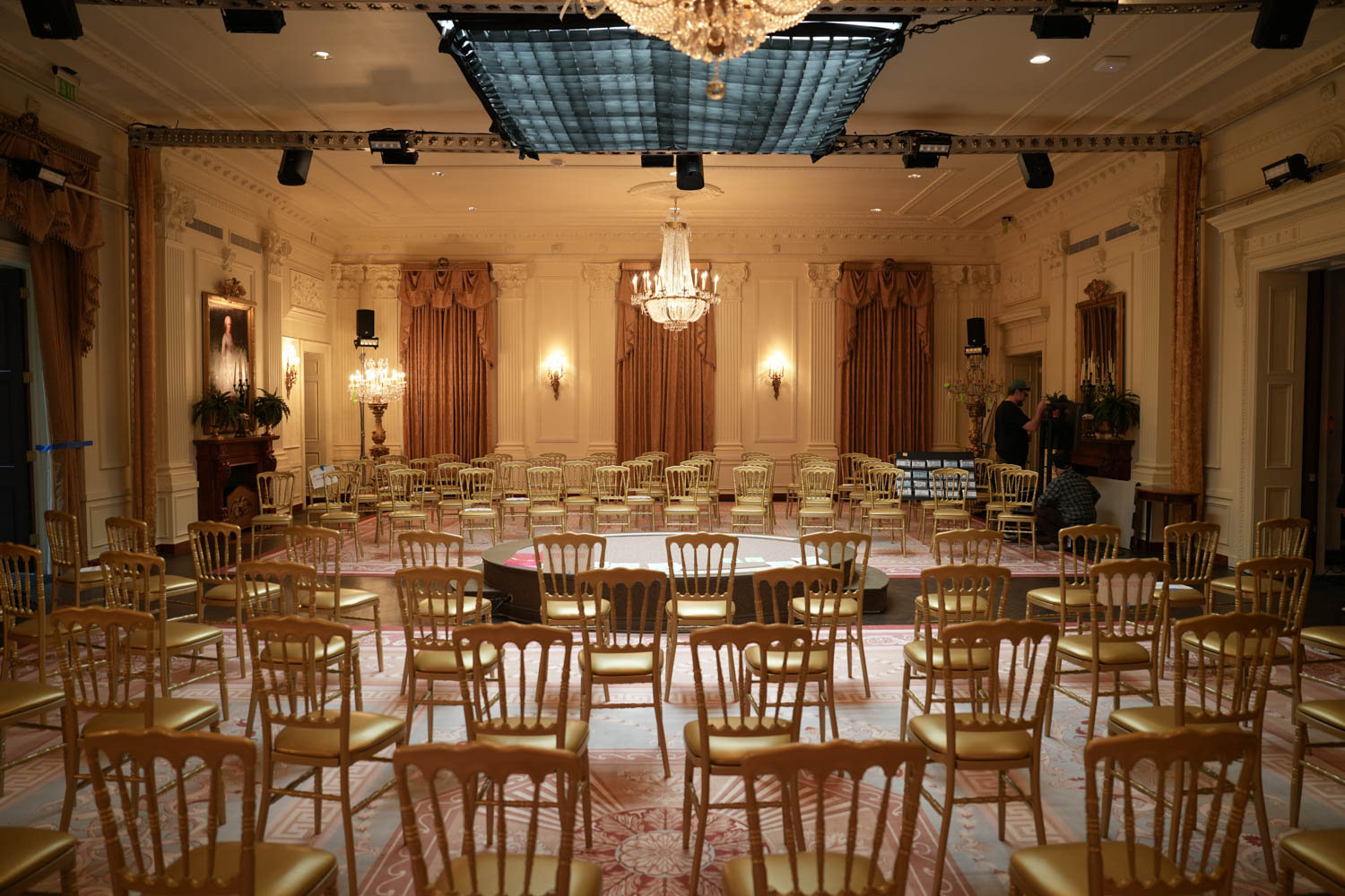 room with dark yellow tones and multiple chairs around a stage