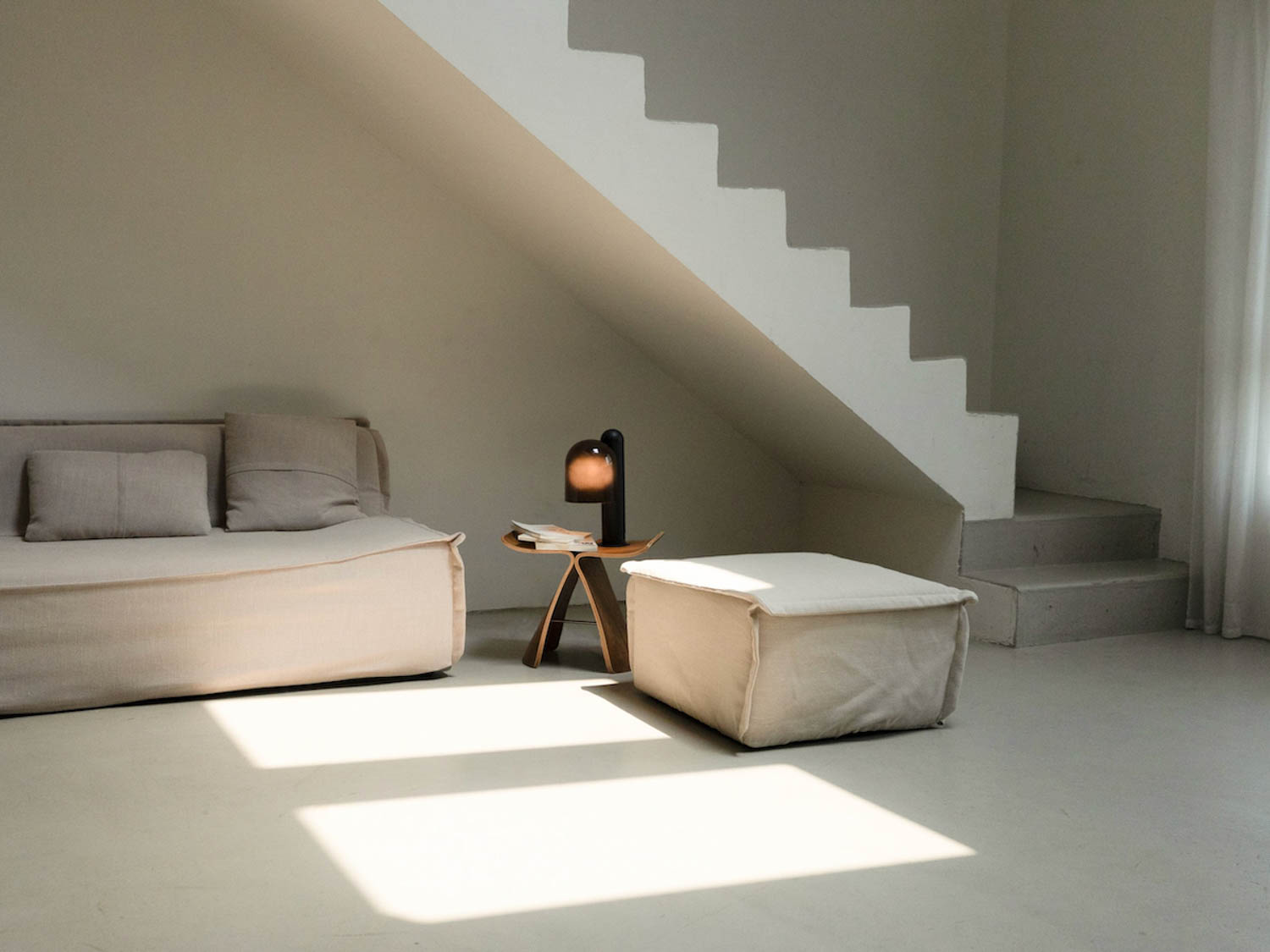 bottom of stairs with a couch and lamp with orange orb