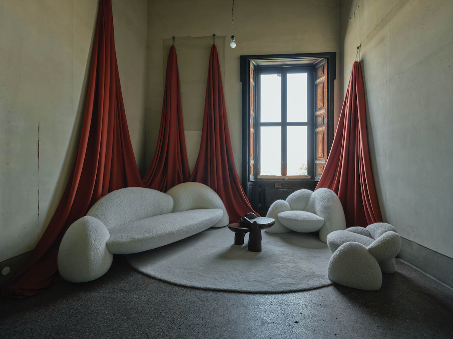 room with multiple white couches and red drapes
