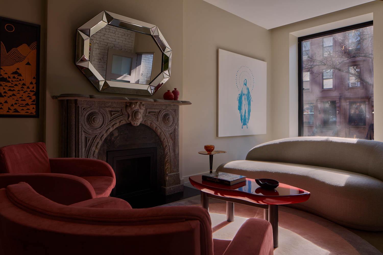 living room area with red chair, fireplace and octagonal mirror