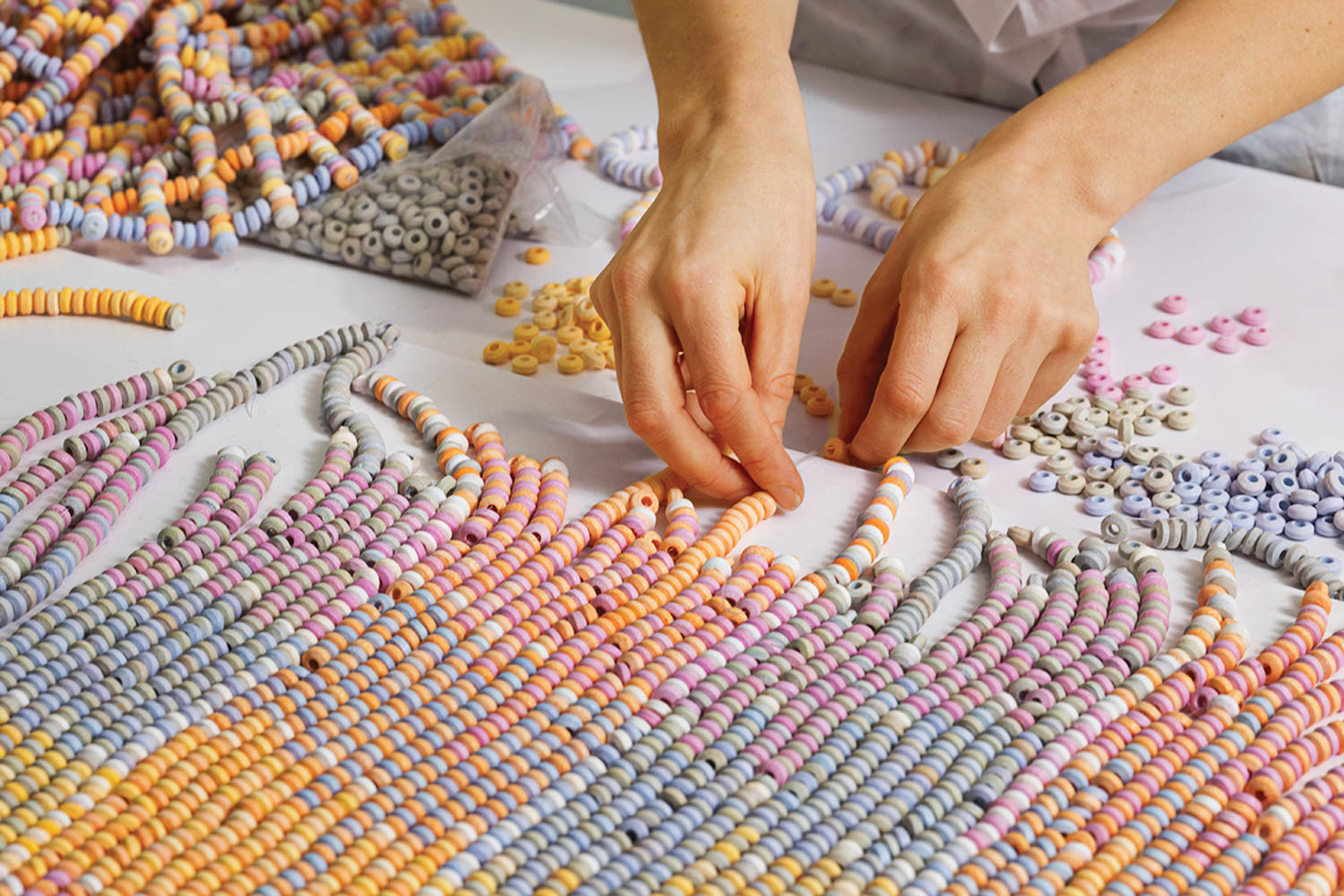 hands putting together candy necklaces