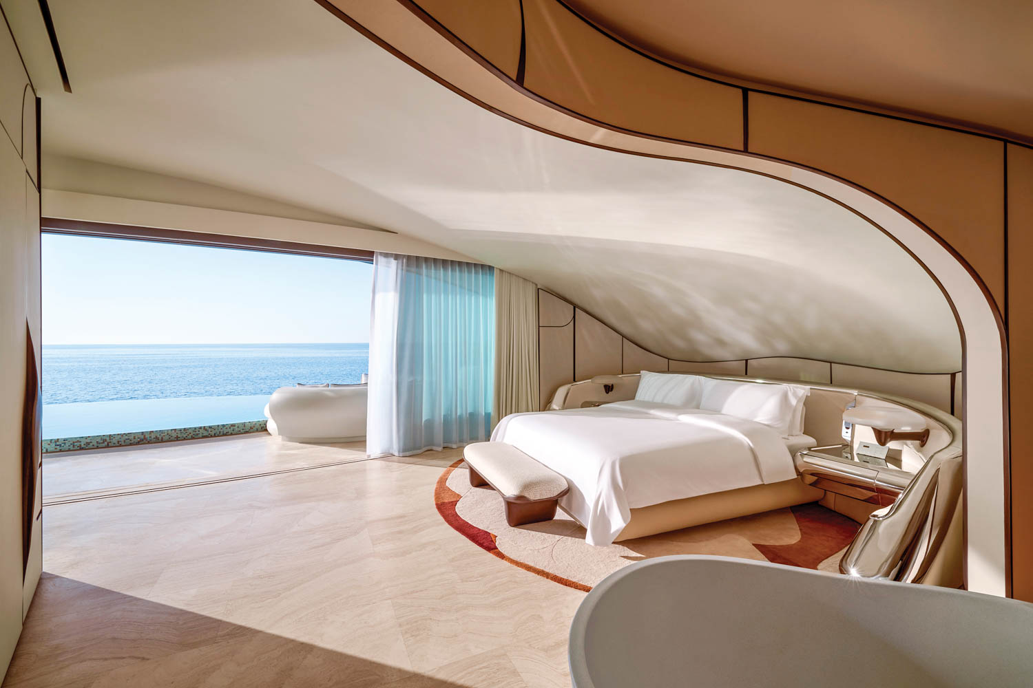 room with plaster ceiling, white bed and bathroom overlooking ocean