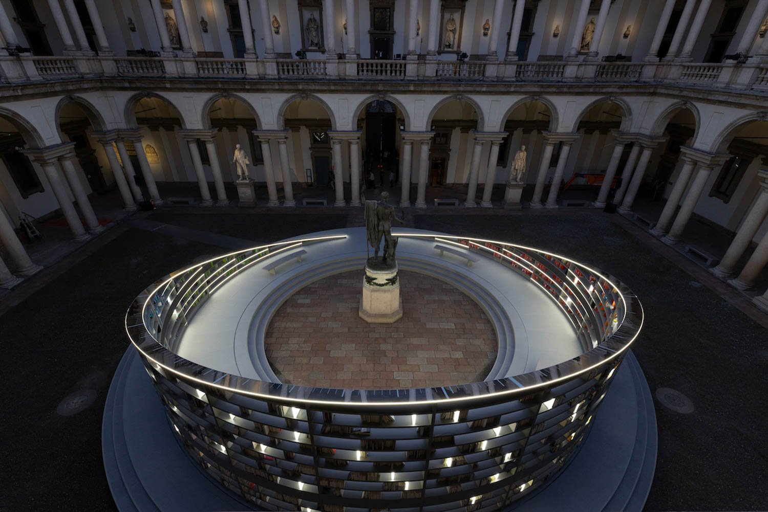 aerial view of statue in a round ring of light and books