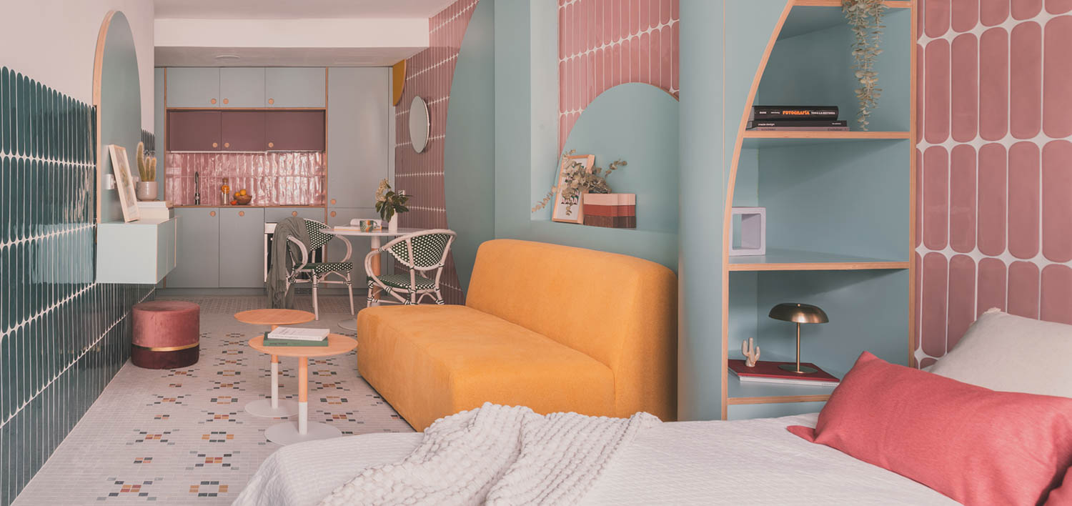 colorful kitchen and living room area with light blue walls, pink tiles and orange couch