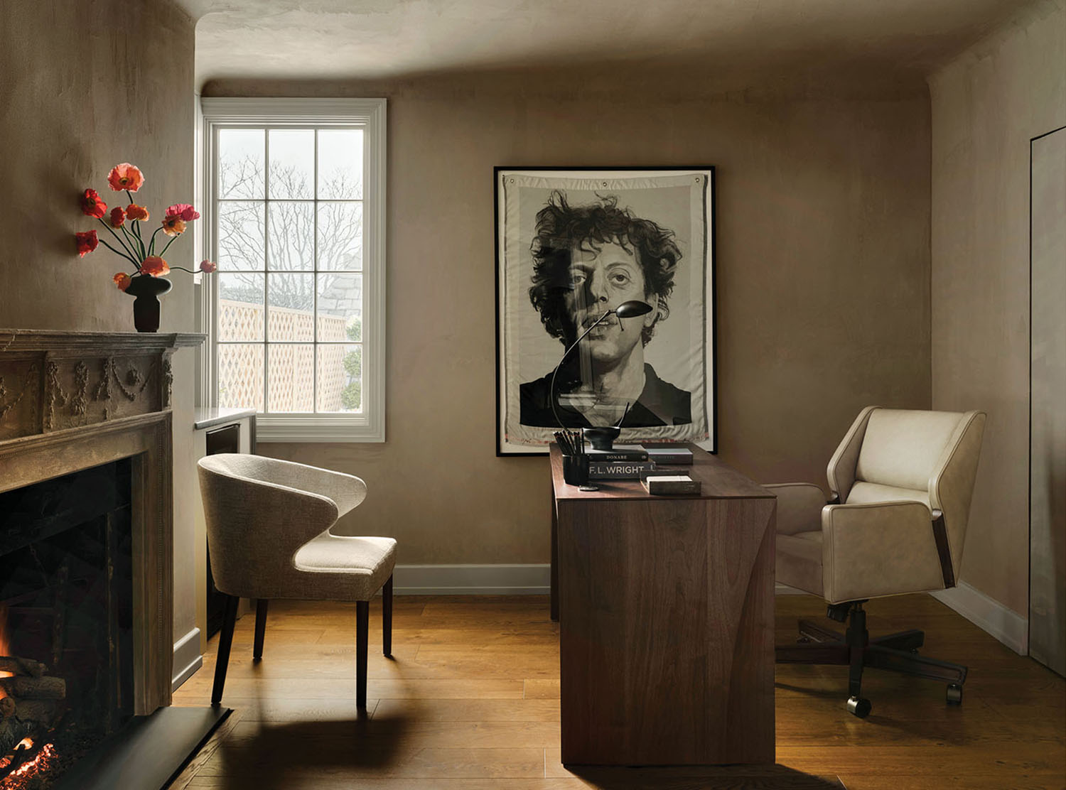 A picture of a woman is on the wall above a fireplace.