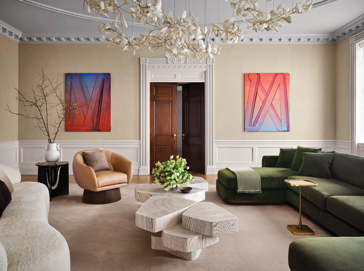 A living room with a large chandel and a green couch.