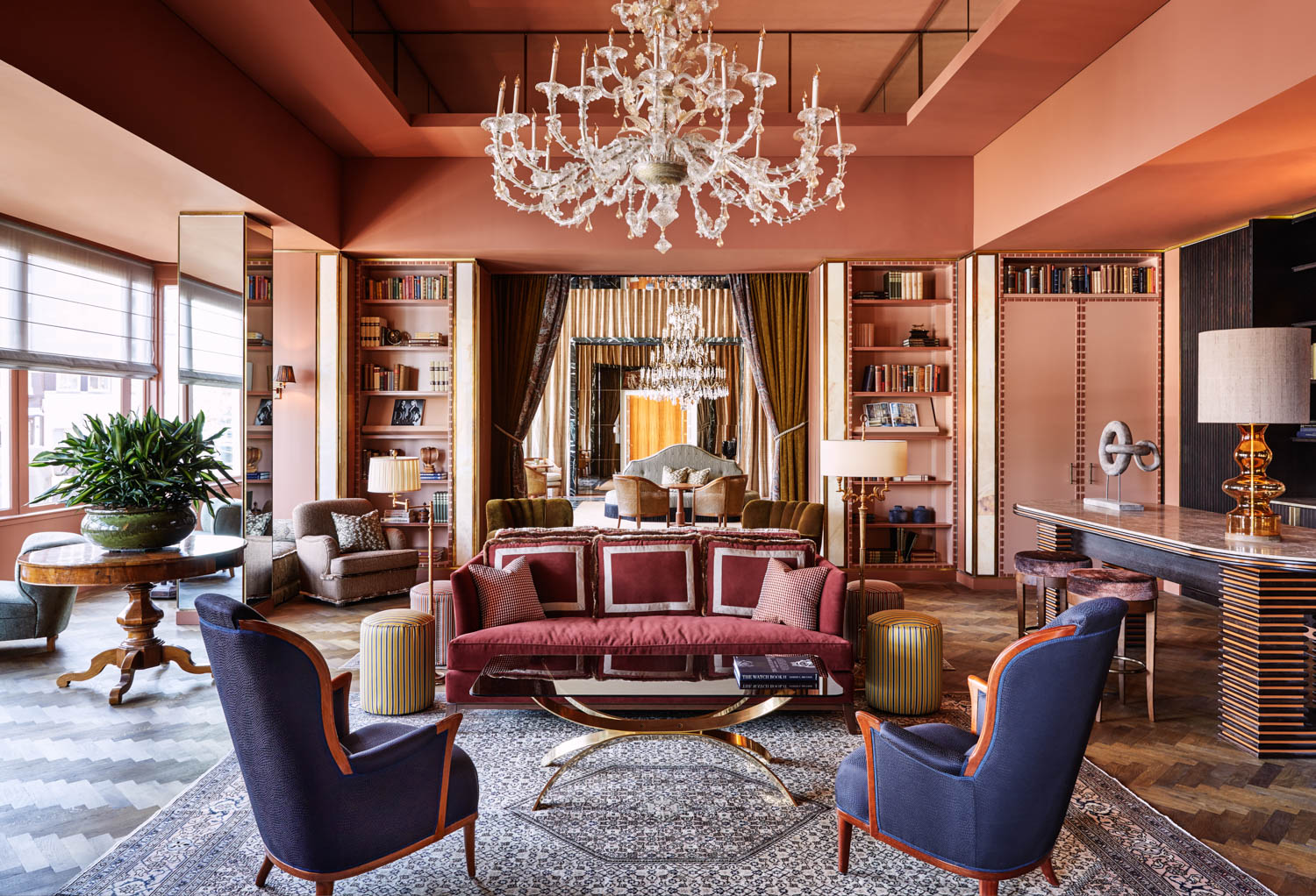library room with coral walls, blue chairs and chandelier